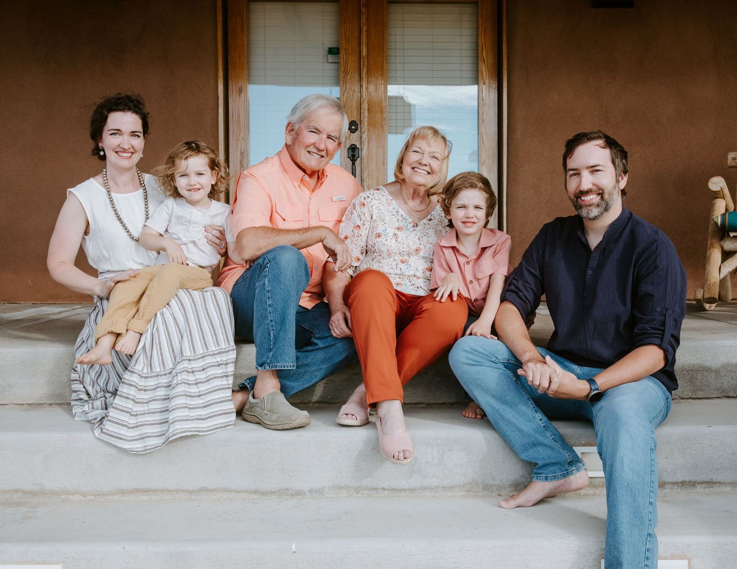A casual family gathering on a porch with everyone sitting close together.