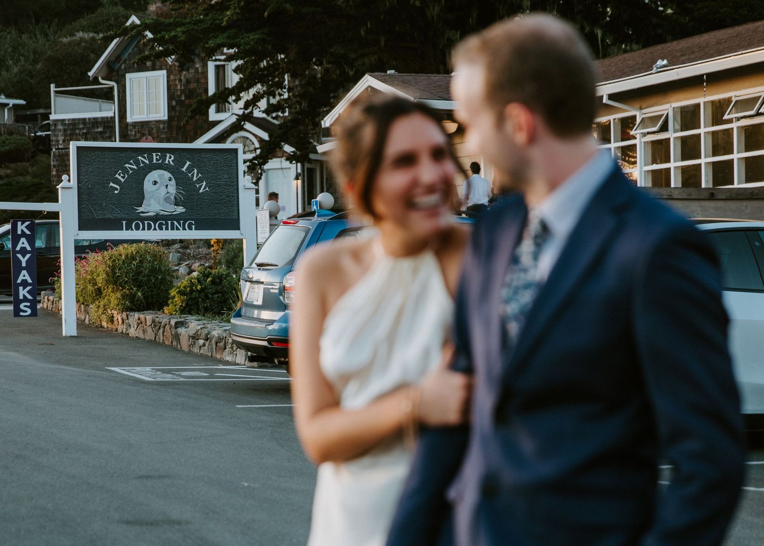 A couple in wedding attire embraces while dancing in an outdoor venue with buildings in the background.