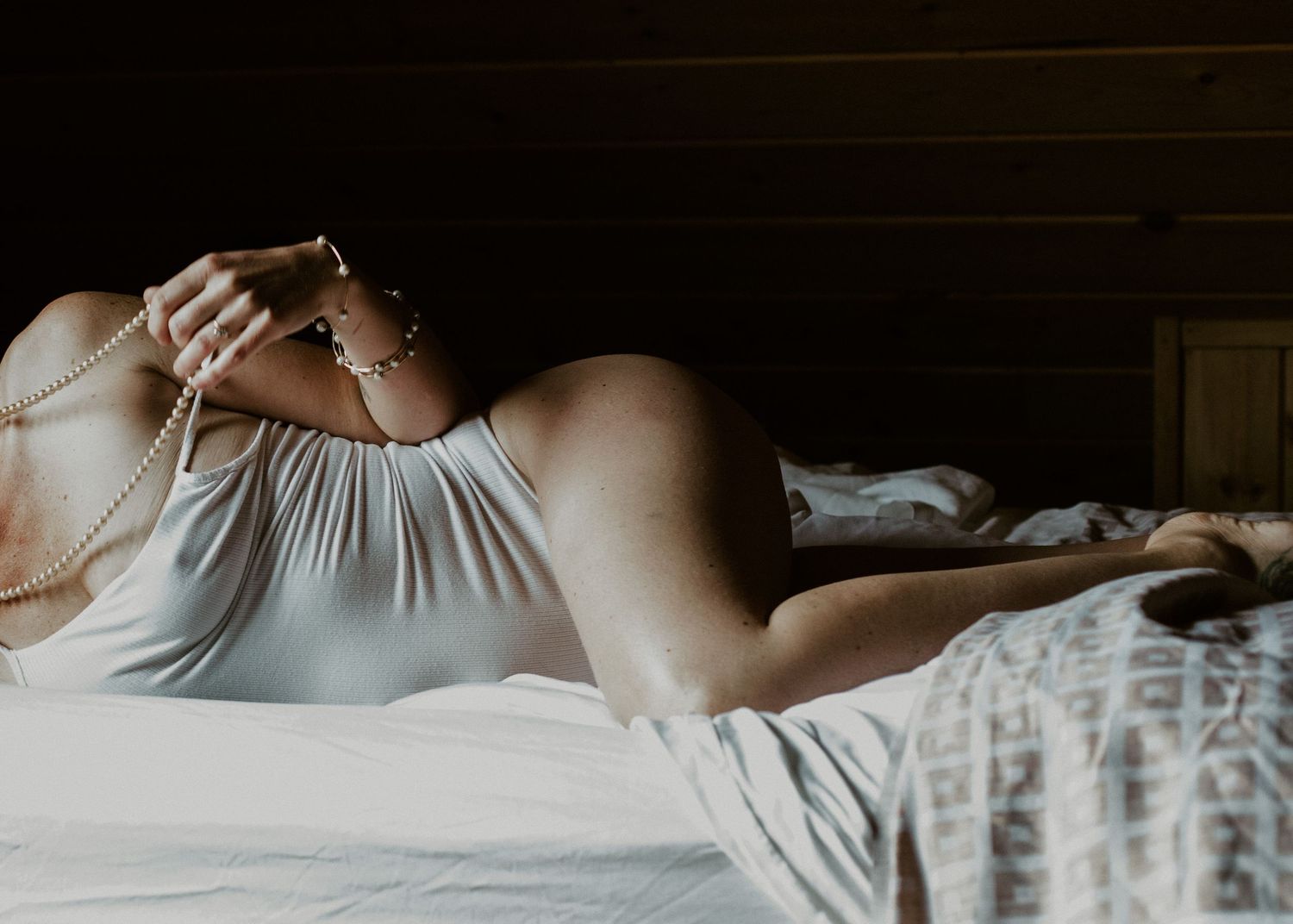 A close-up view of someone resting on white bedding in soft natural light.