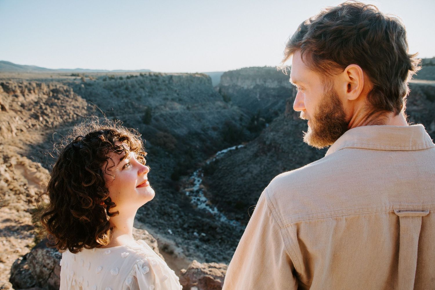 Couple in casual attire enjoying a scenic mountain overlook during golden hour.