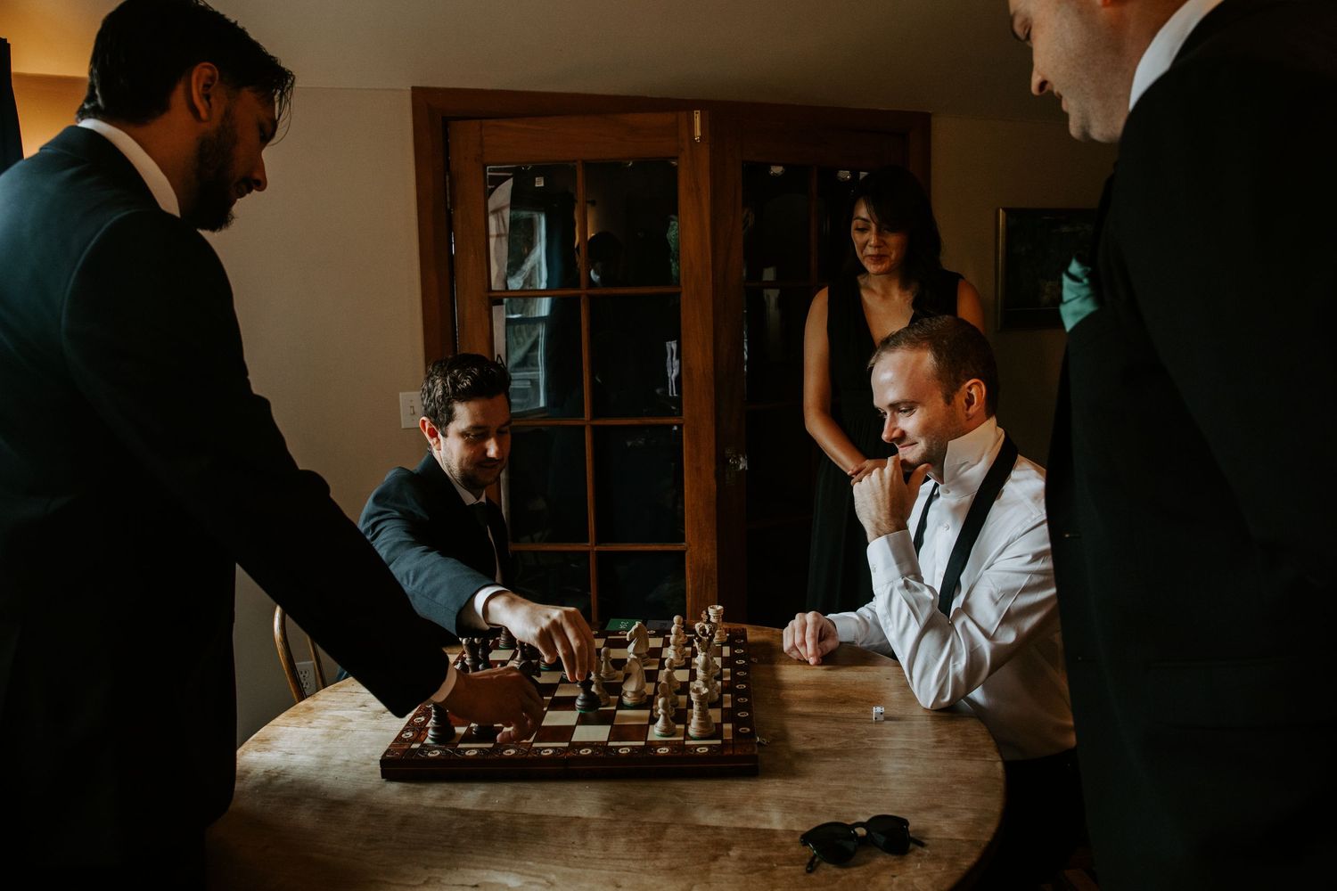 Wedding guests gathered indoors around tables with champagne glasses.