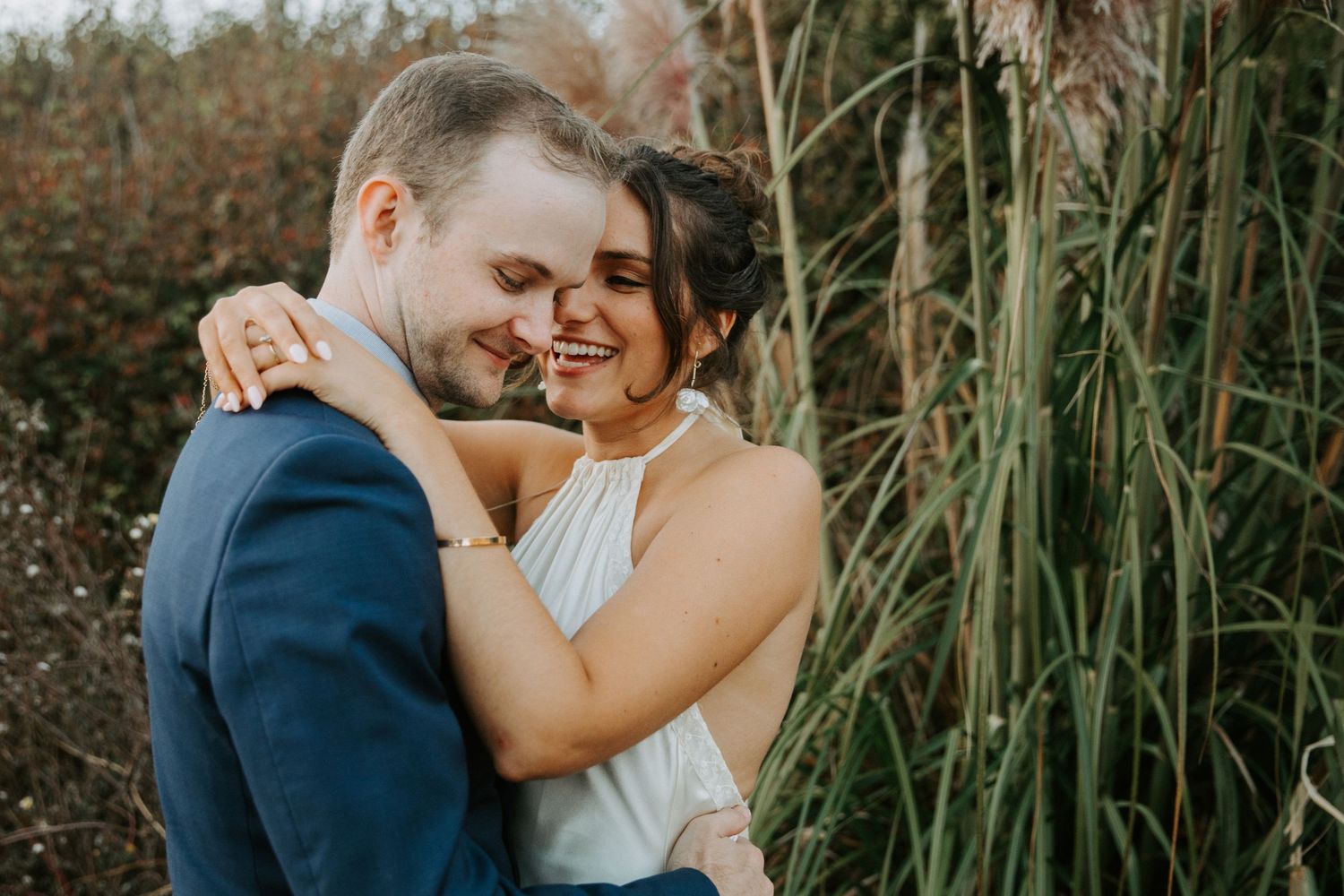 A couple shares intimate romantic moments in tall grass during an outdoor photo session.
