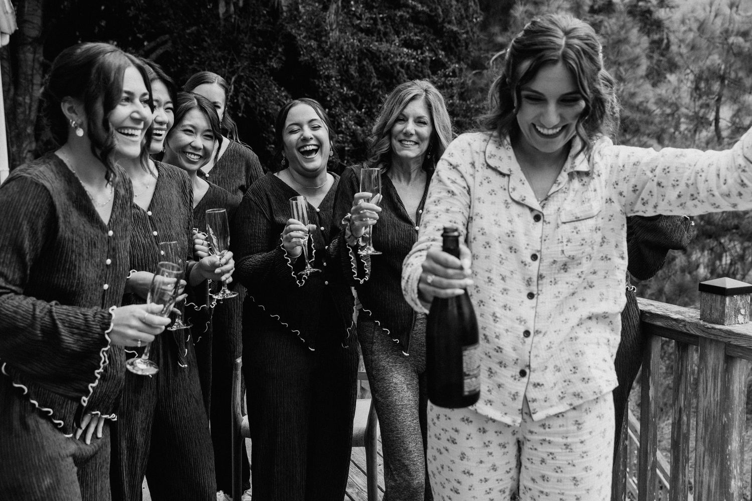 Wedding celebration with guests holding champagne glasses and laughing together.