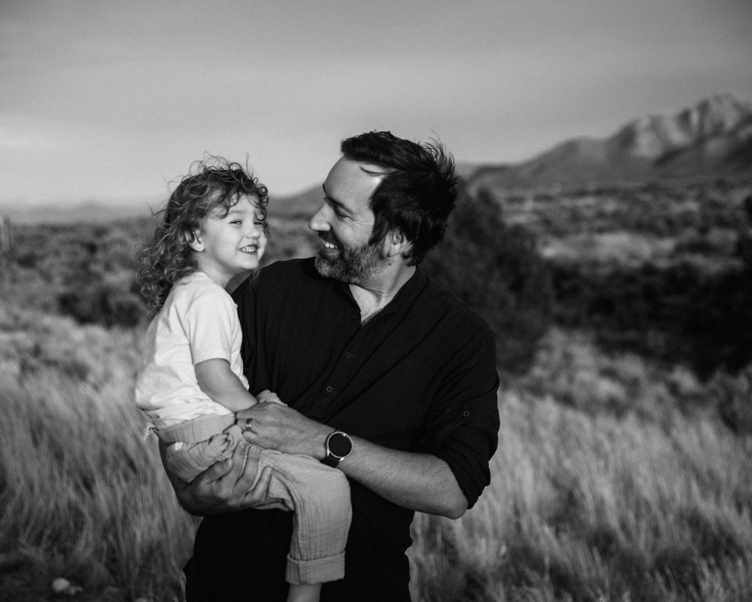 Black and white photos capturing tender moments between two people in an outdoor setting with mountains.