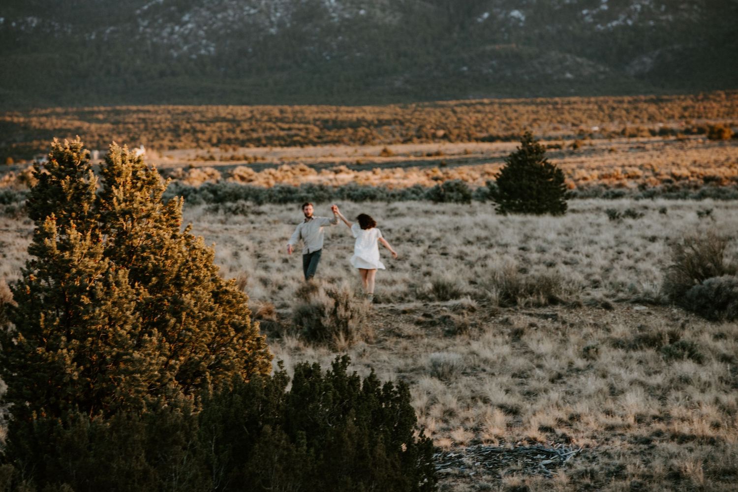 Couple walking through expansive desert landscape during a Taos New Mexico engagement session at sunset