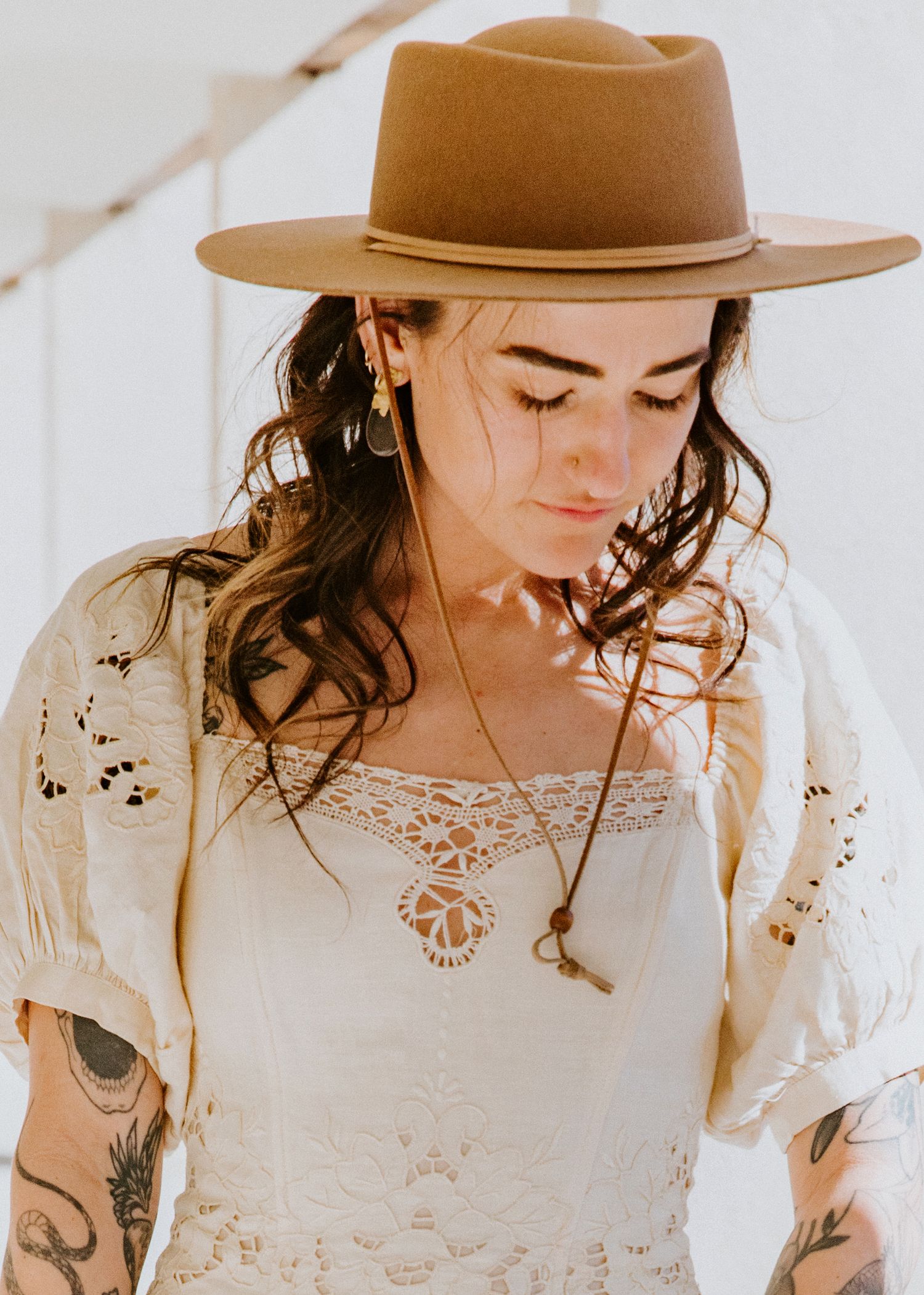 A woman in a brown hat and white lace dress poses in multiple artistic shots against a light background.