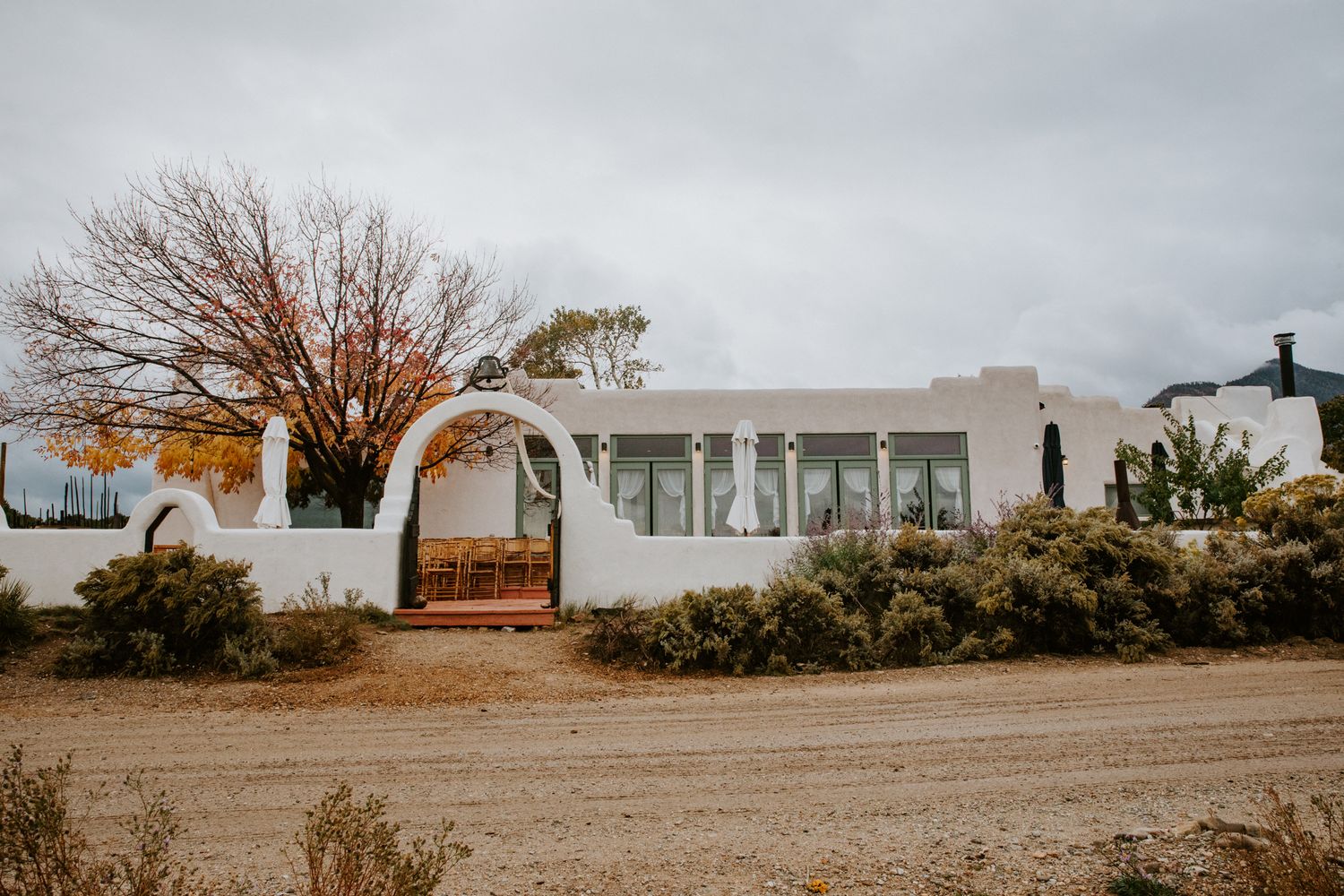 Panoramic view of a rural landscape with bare trees and buildings under cloudy skies.
