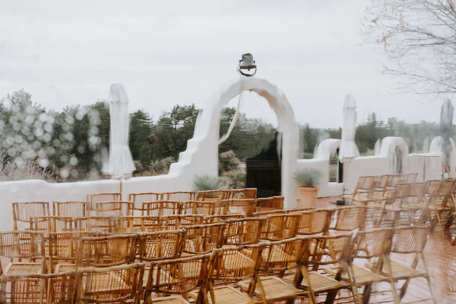 Rows of wooden chairs set up outdoors for a rustic wedding ceremony with mountains visible in the background.