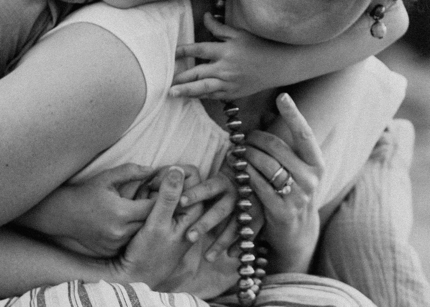 Black and white close up image of someone talking on a vintage rotary phone while lying down.