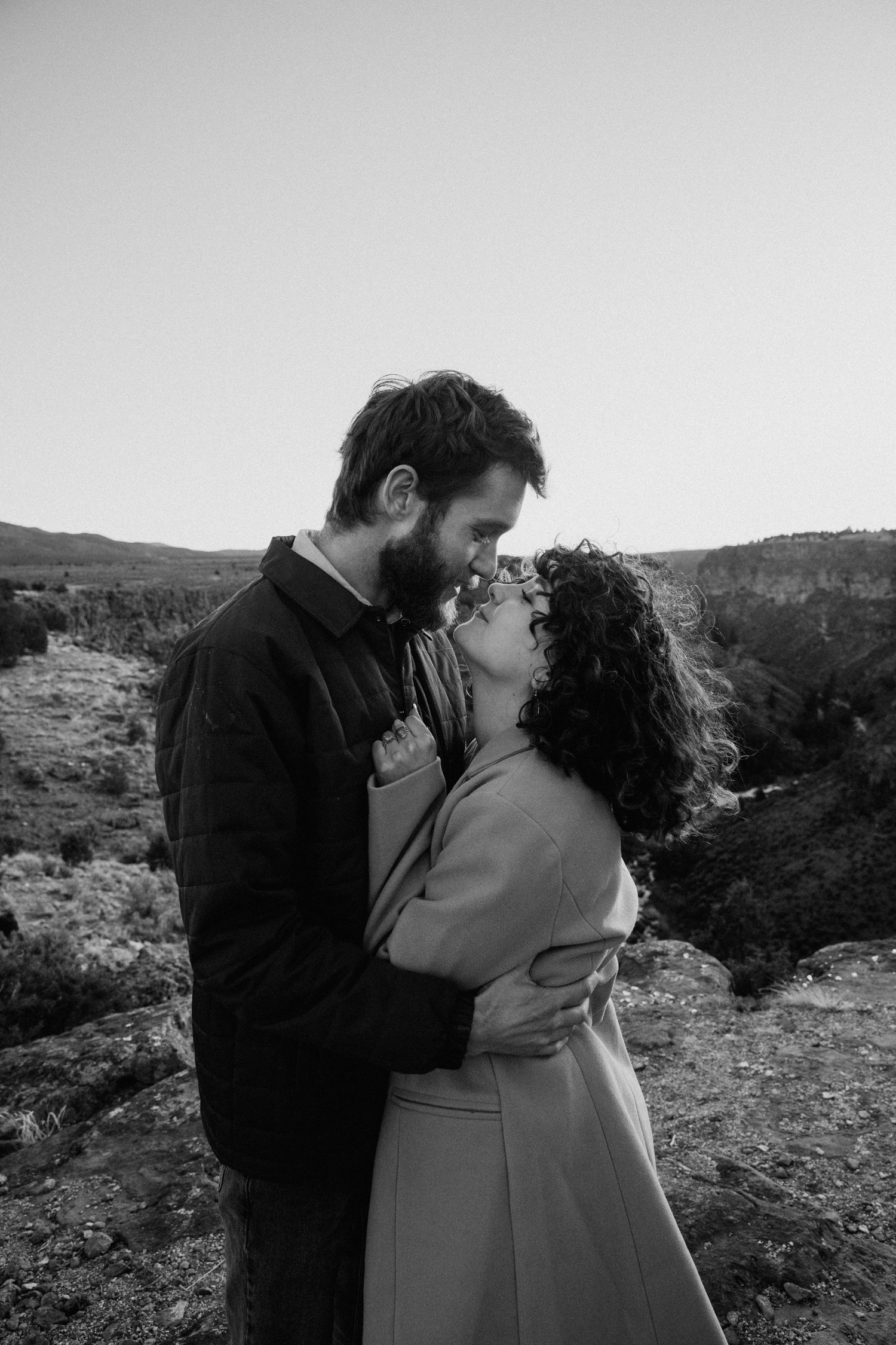 Black and white engagement session in Taos NM with couple sharing a quiet moment in a mountain landscape
