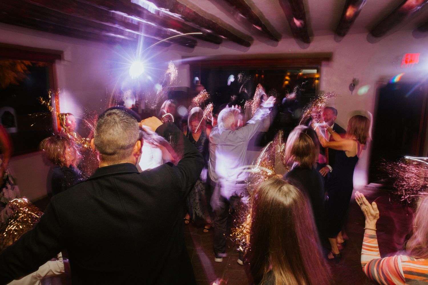 A dark nightclub scene with colorful lights and silhouettes of people dancing on a crowded dance floor.