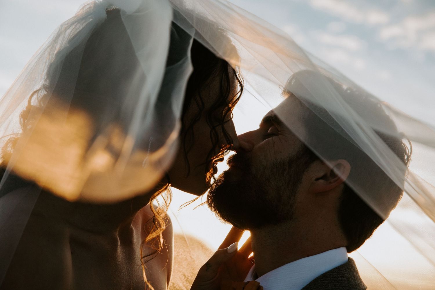 Romantic silhouetted couple embracing at sunset with dramatic sky and lens flare creating ethereal atmosphere.  Shot in Taos, NM by Siouxzen