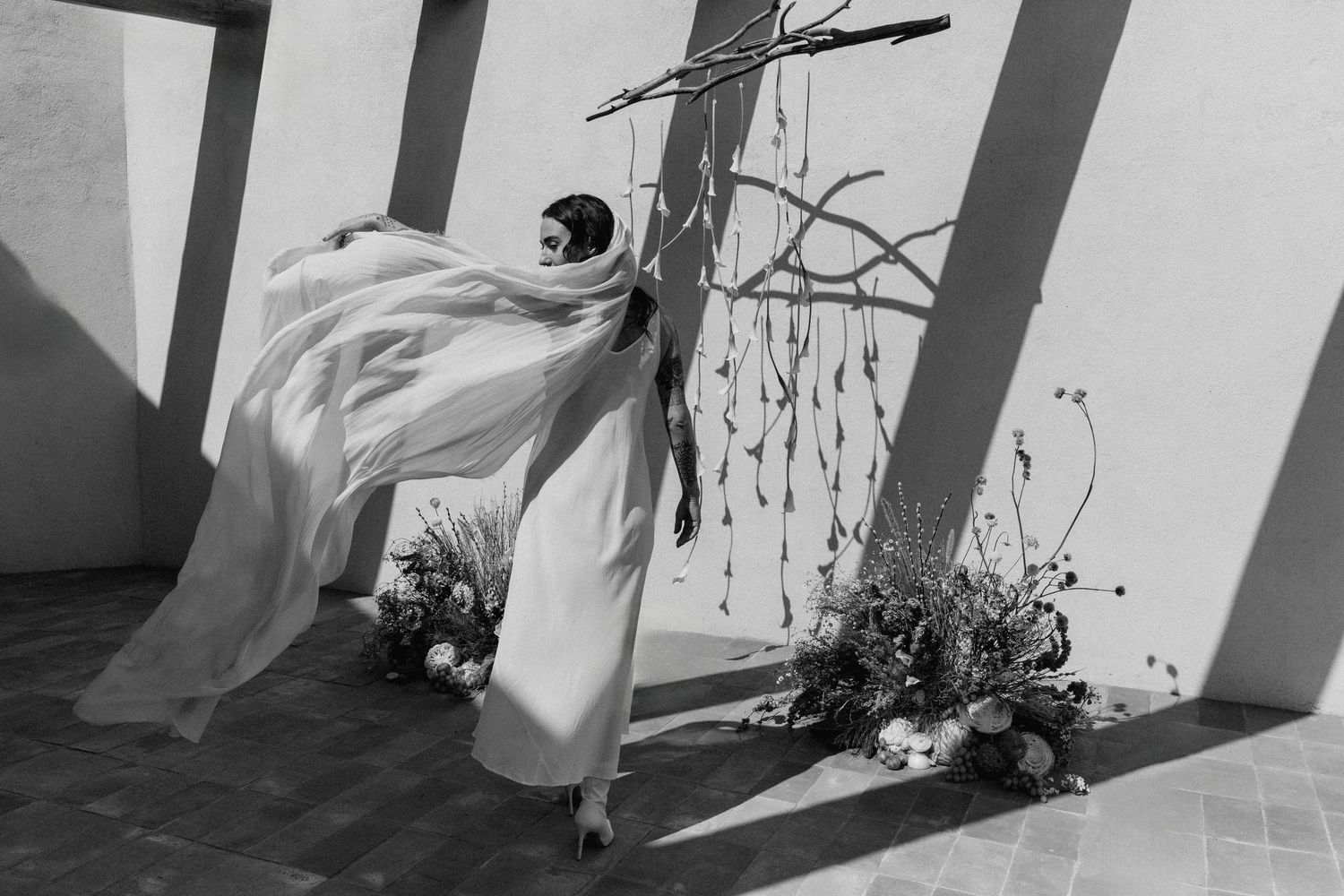 A black and white photo series showing a figure in flowing fabric moving through architectural spaces.