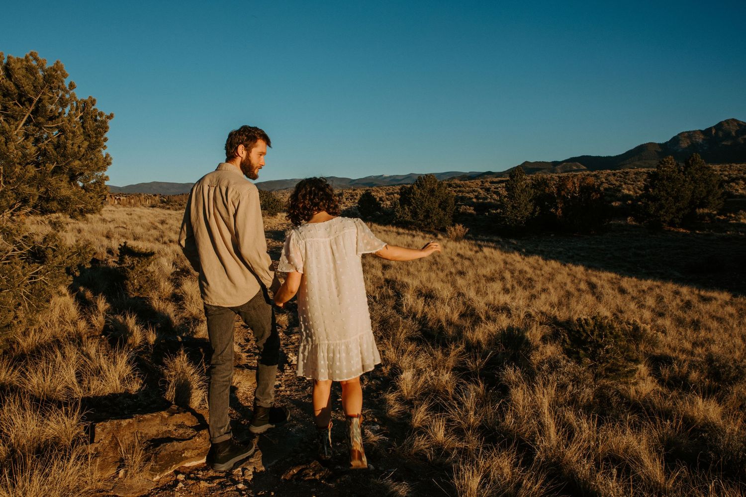 Couple walking hand in hand during a Taos New Mexico engagement session at golden hour