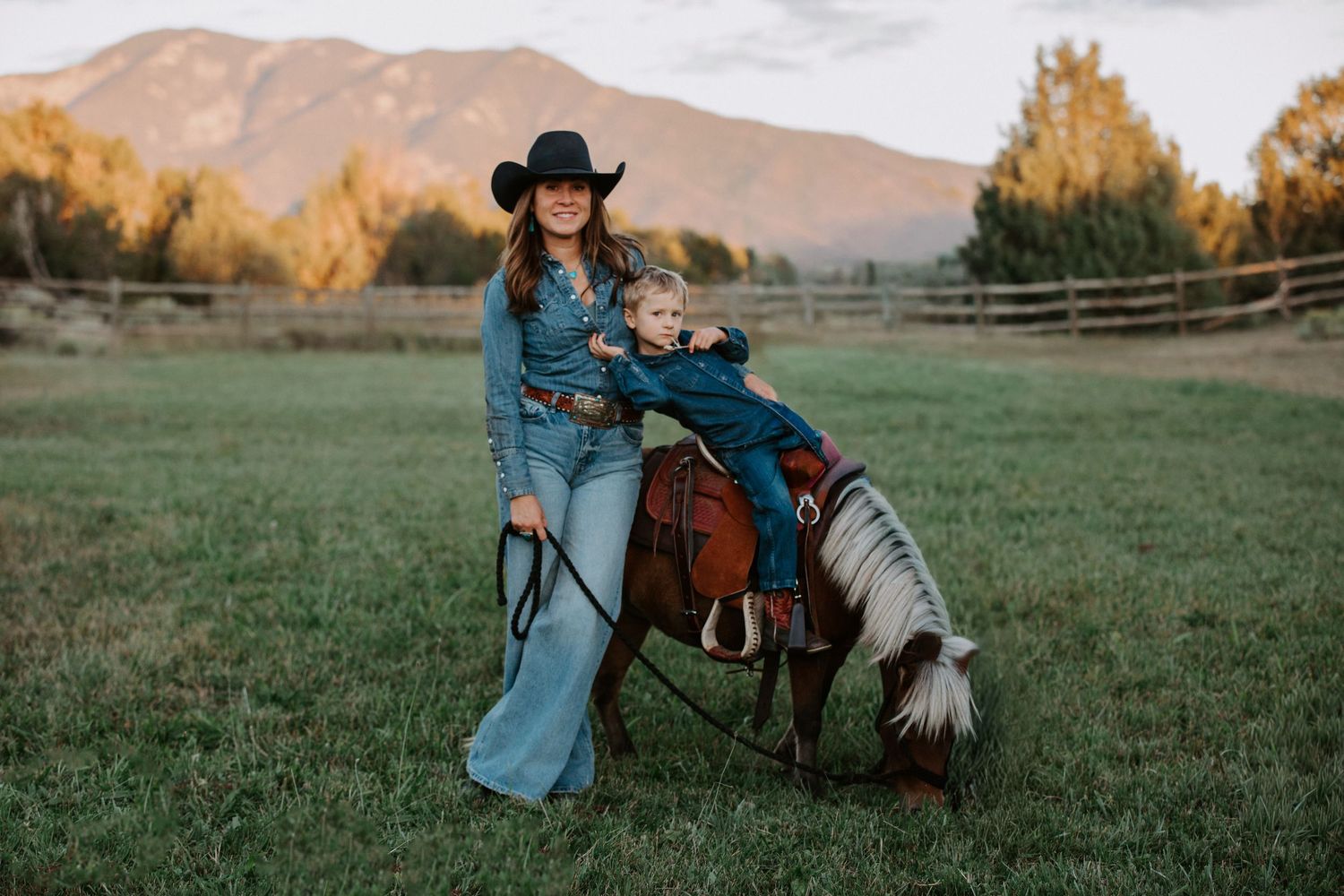 Western scene with horses grazing in mountain meadow at golden hour.  Shot in Taos, NM by Siouxzen Kang