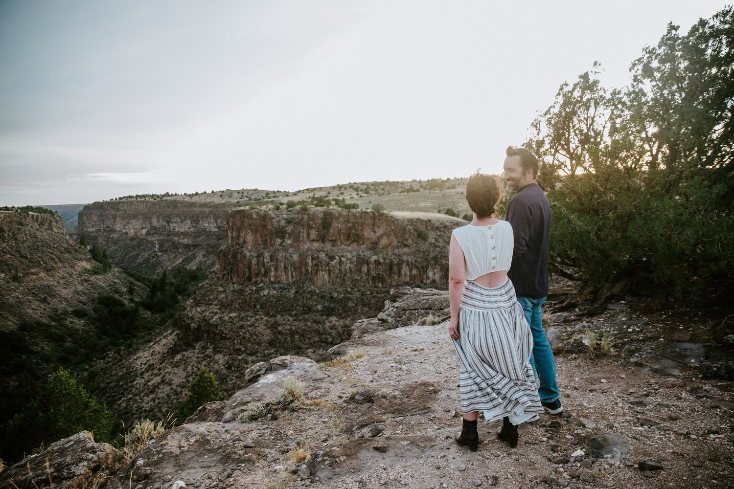 People enjoying a scenic overlook at sunset in a rocky desert landscape with dramatic canyon views in the background.