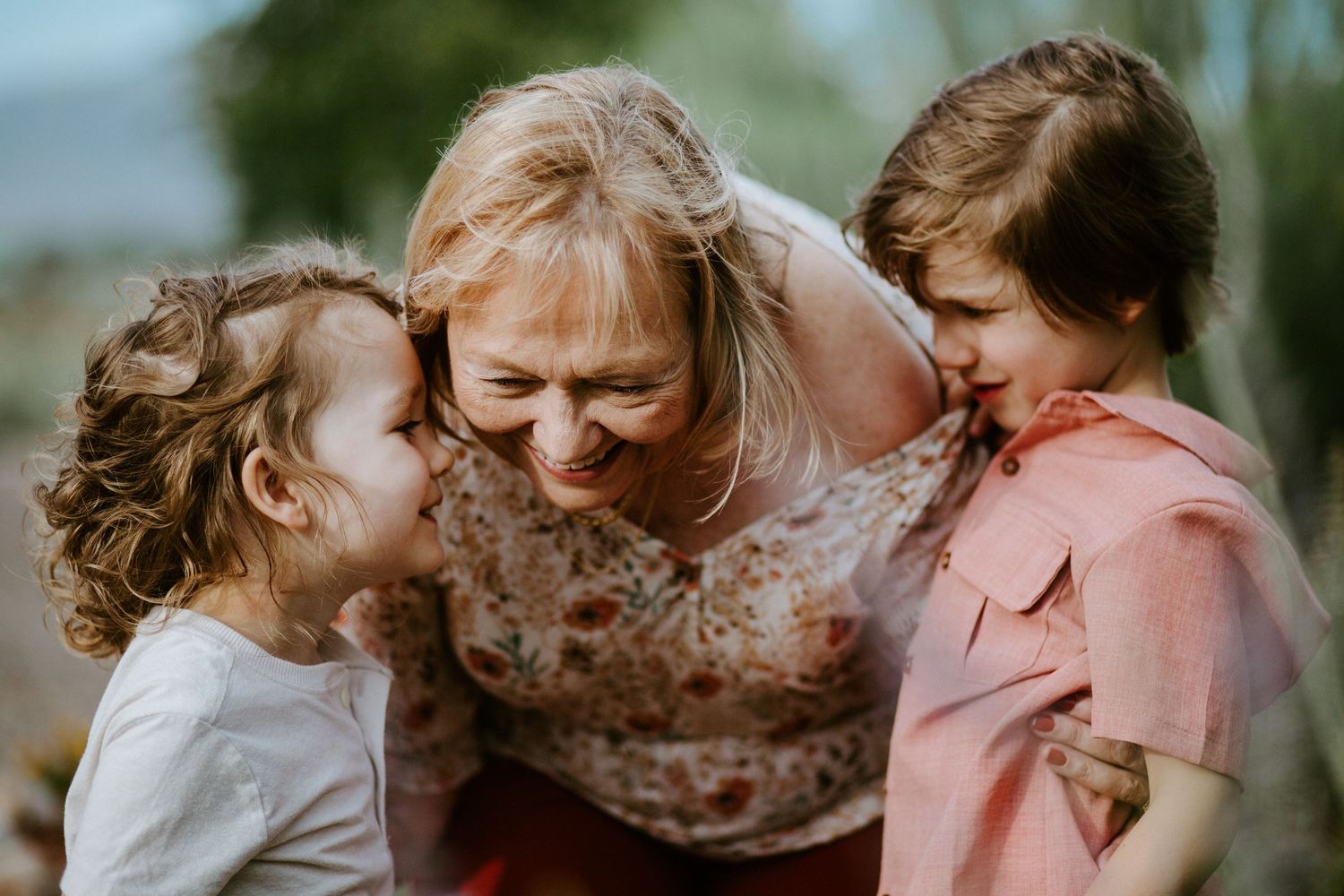 Family members share intimate moments of laughter and affection in an outdoor setting.