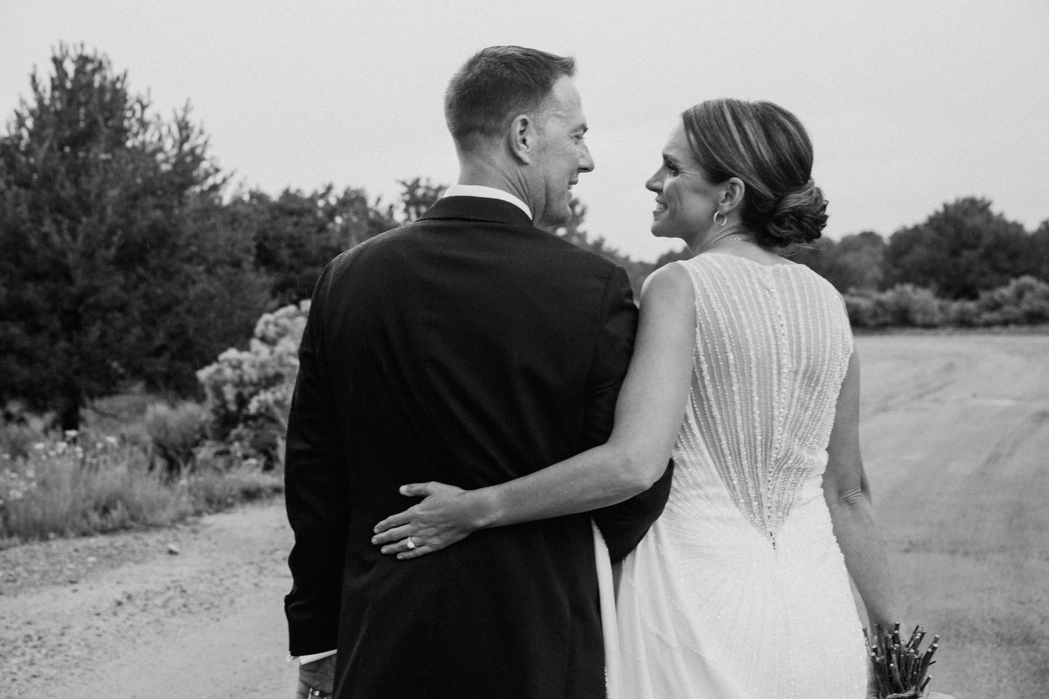 A romantic black and white photo series shows a couple embracing and walking together on a scenic outdoor path.