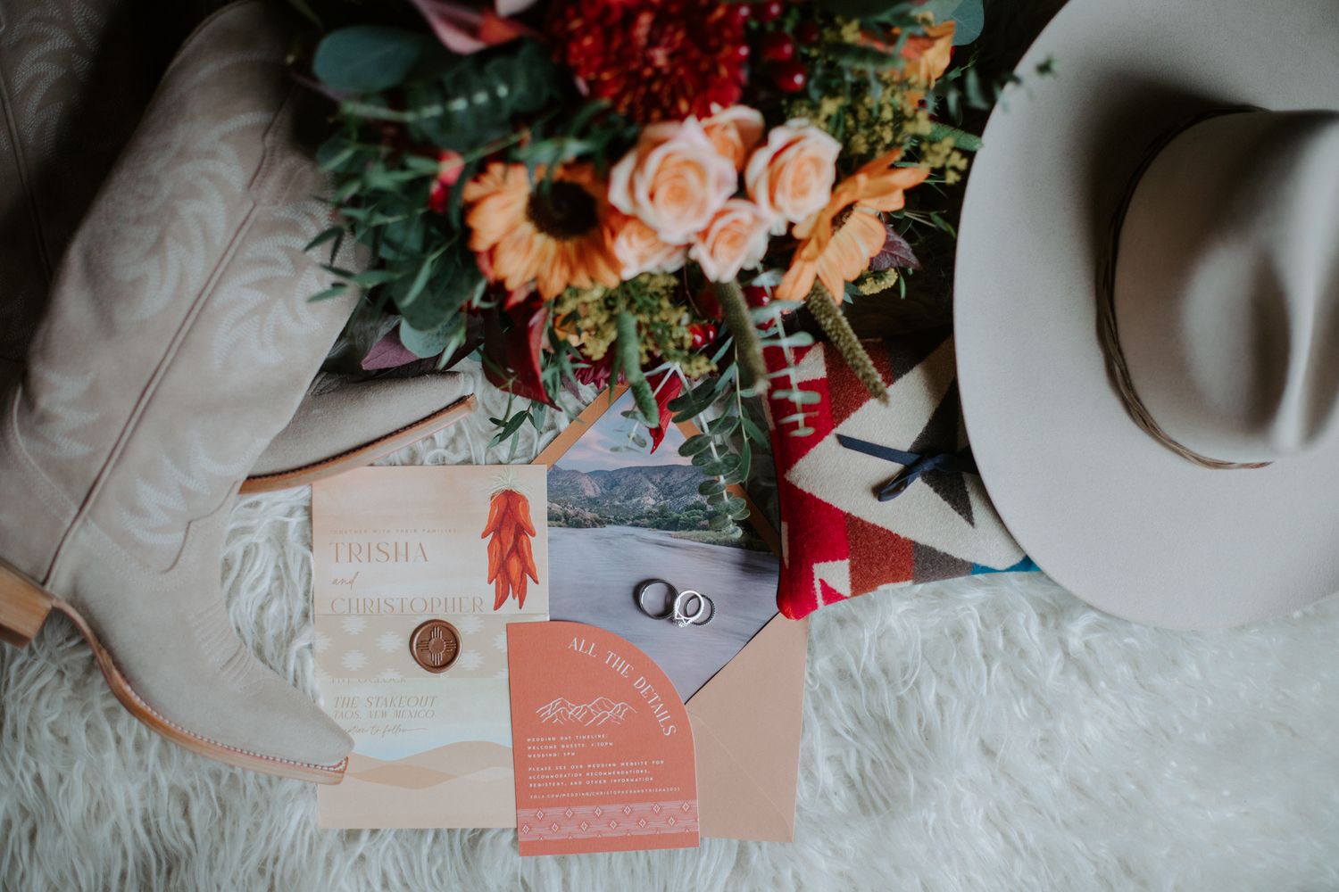 Wedding stationery and floral arrangements in peach and burgundy tones on a light surface.