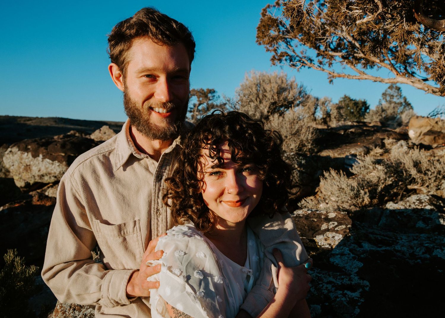 A couple embraces while enjoying the desert landscape during golden hour at Joshua Tree National Park.