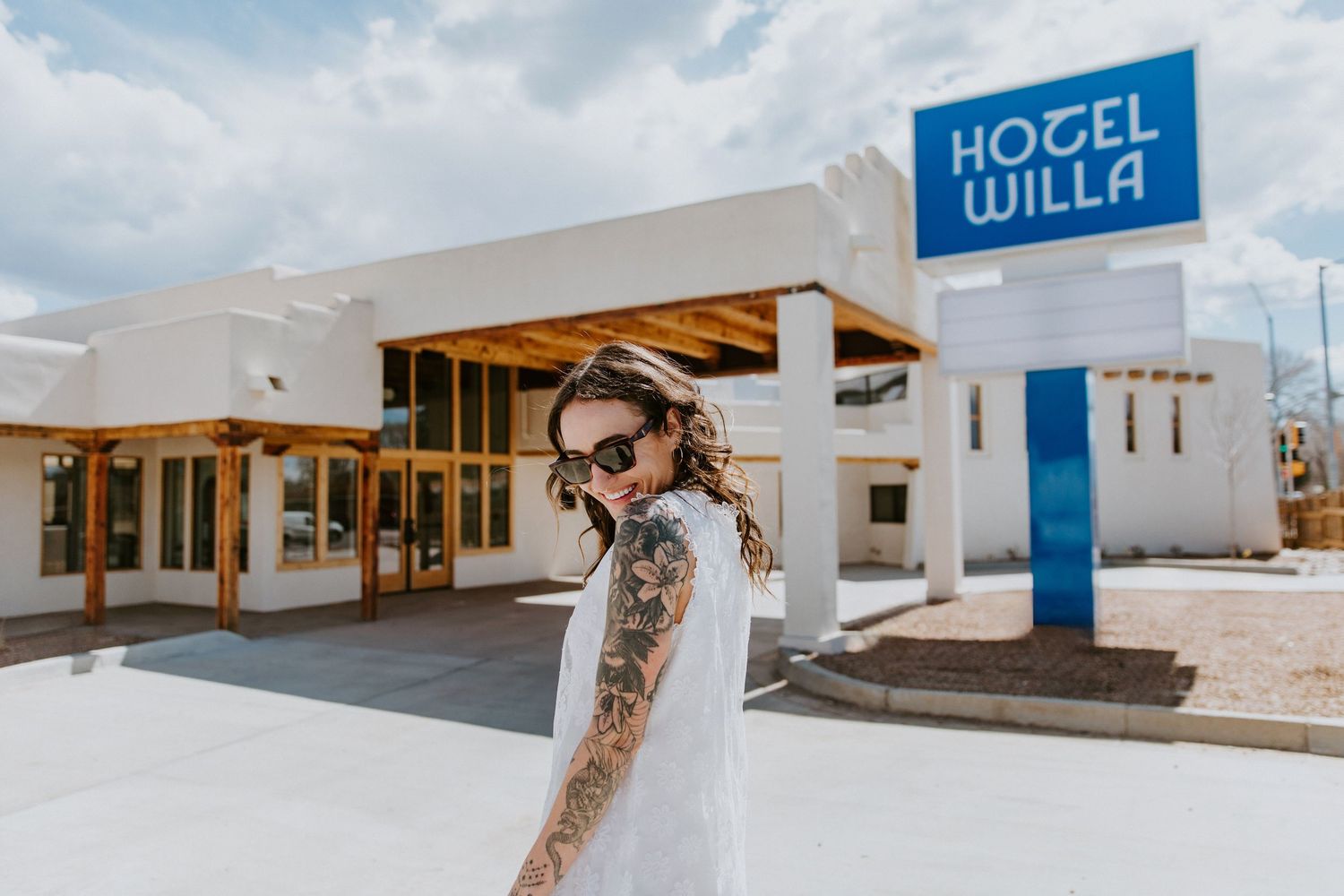 A panoramic collage of white buildings and structures at a coastal resort with blue signage against a bright sky.
