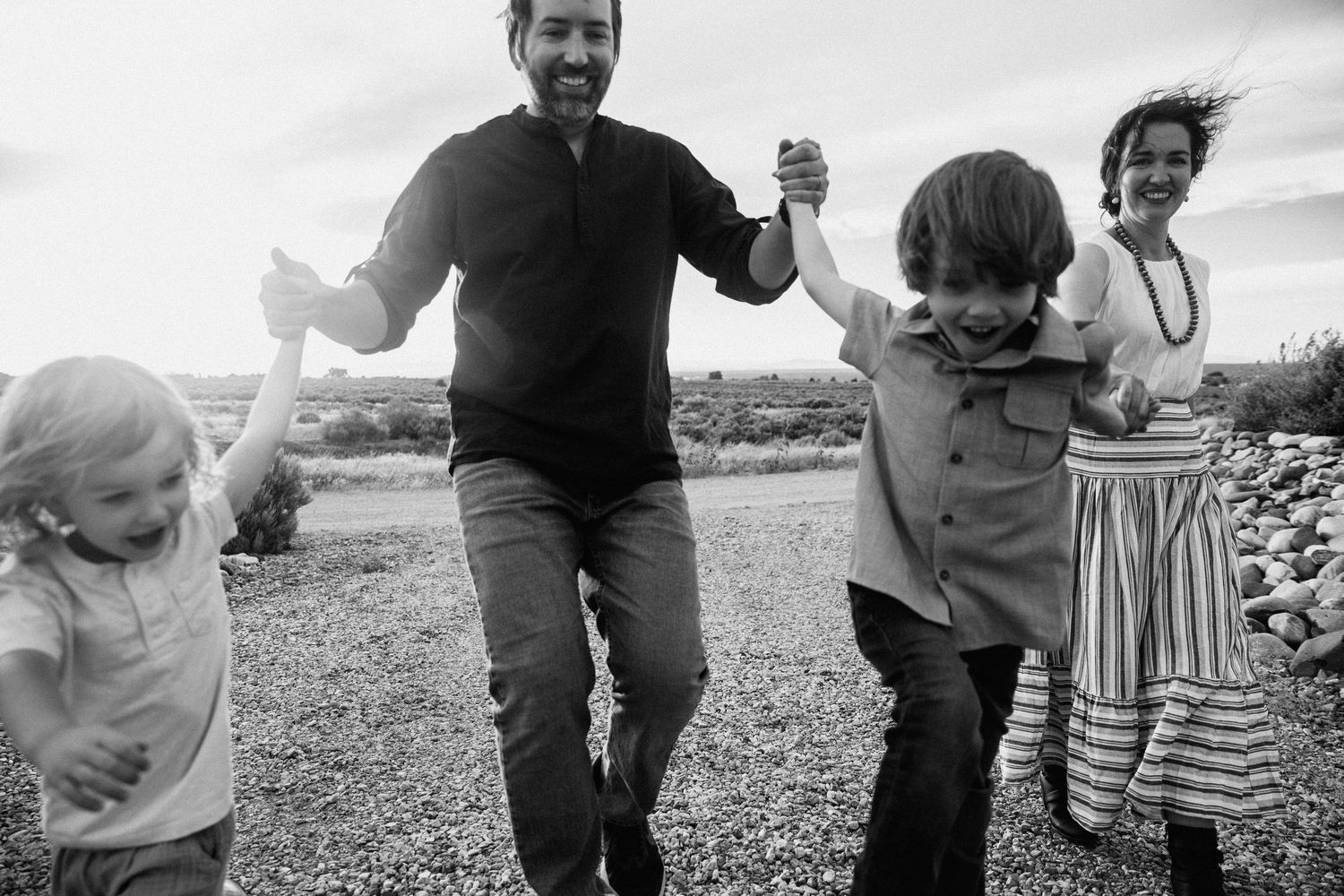 Family enjoying a playful moment together outdoors in black and white.