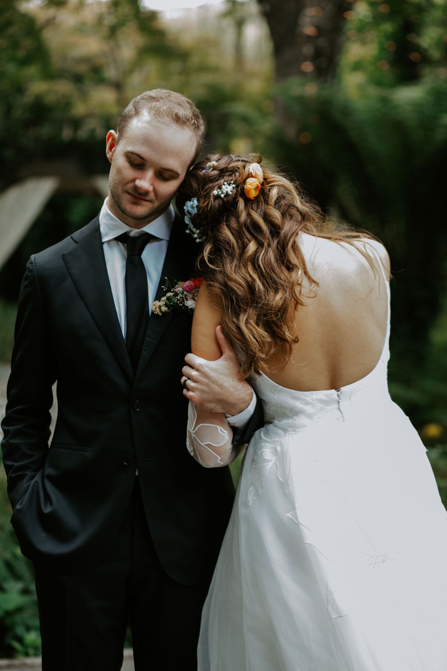Intimate wedding moment captured in a forest setting with natural lighting.