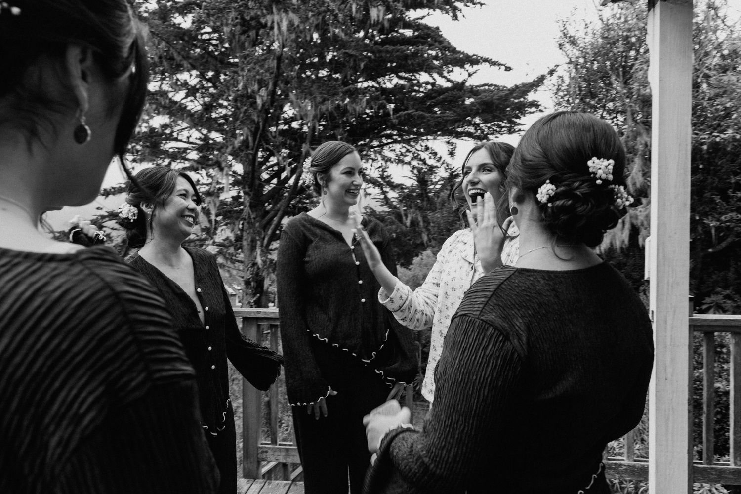 Group of wedding guests mingling outdoors in a garden setting.