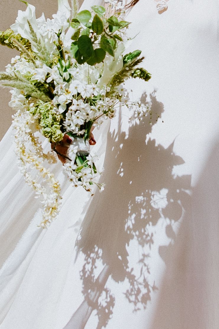 Delicate white flowers cast intricate shadows against a light neutral background in a minimalist composition.