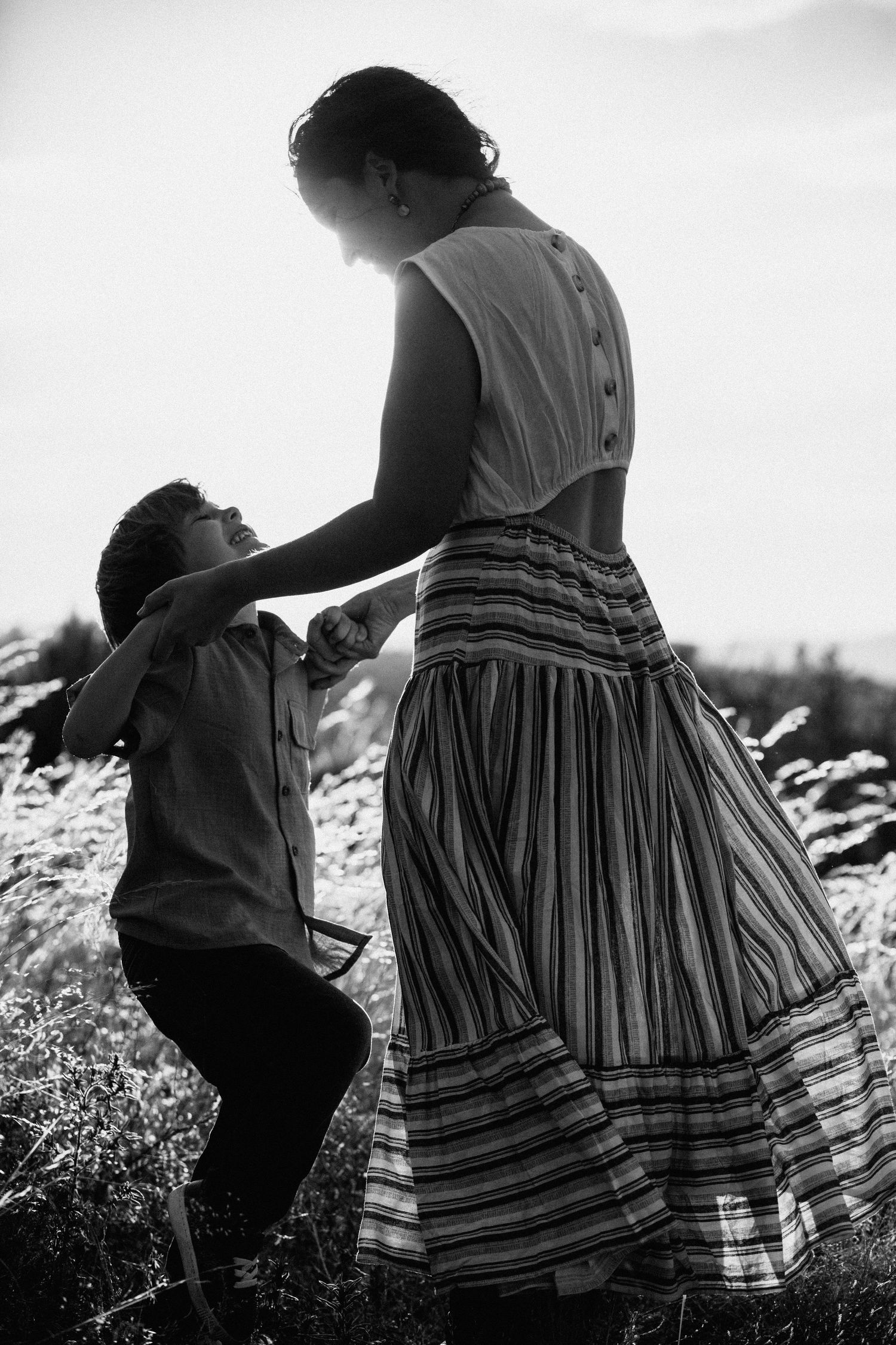Black and white sequence of two people in a field sharing a tender moment in striped vintage dress.