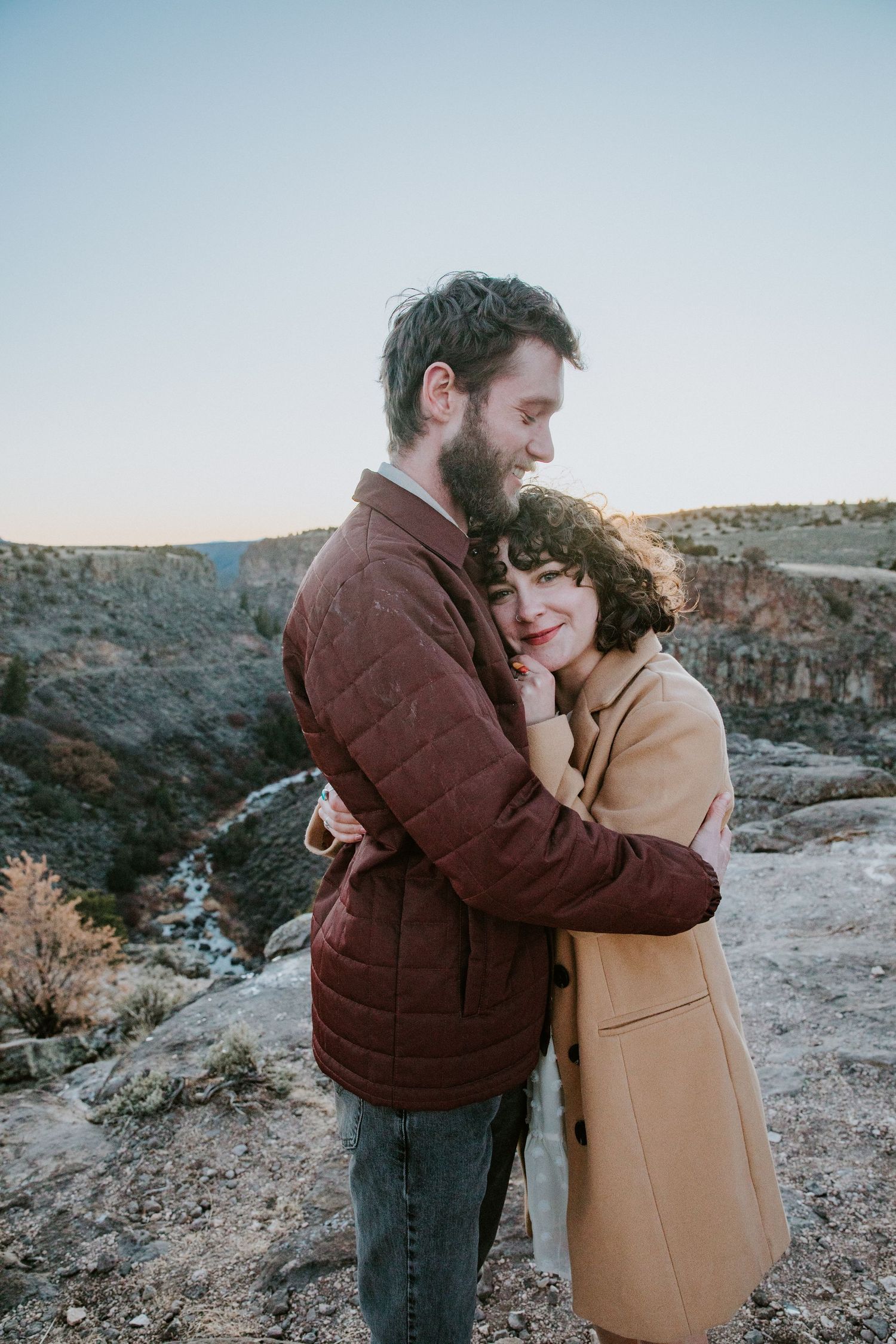 Couple embracing during a golden hour engagement session in Taos, New Mexico desert landscape