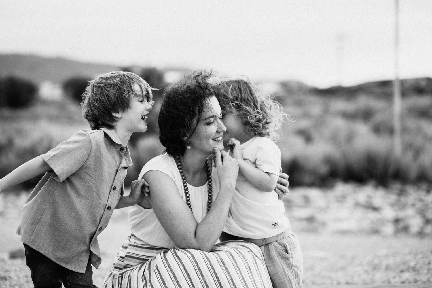 Series of candid black and white shots showing affectionate family moments outdoors.