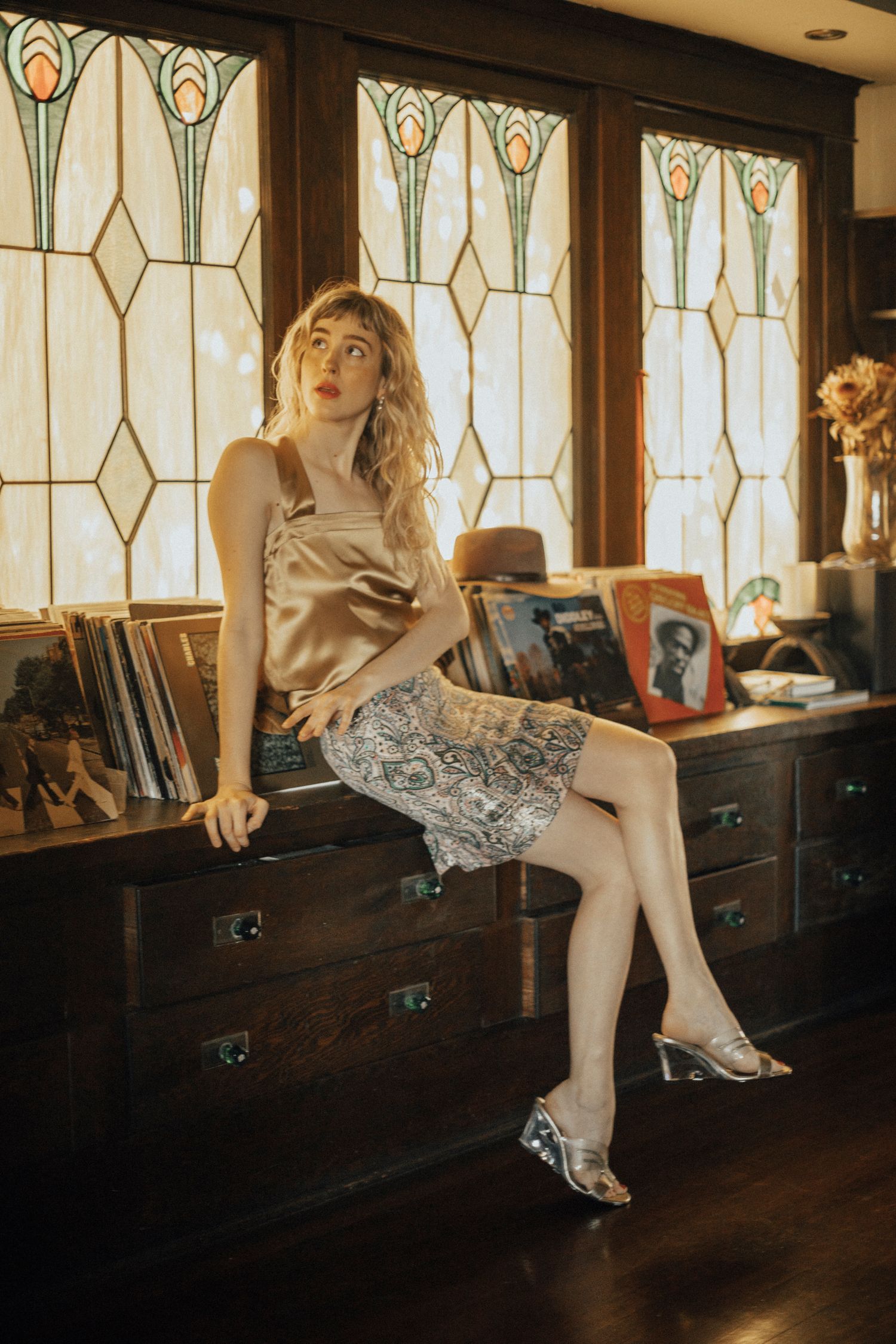 Vintage-inspired fashion shoot with stained glass windows and wooden furniture creating warm ambiance.