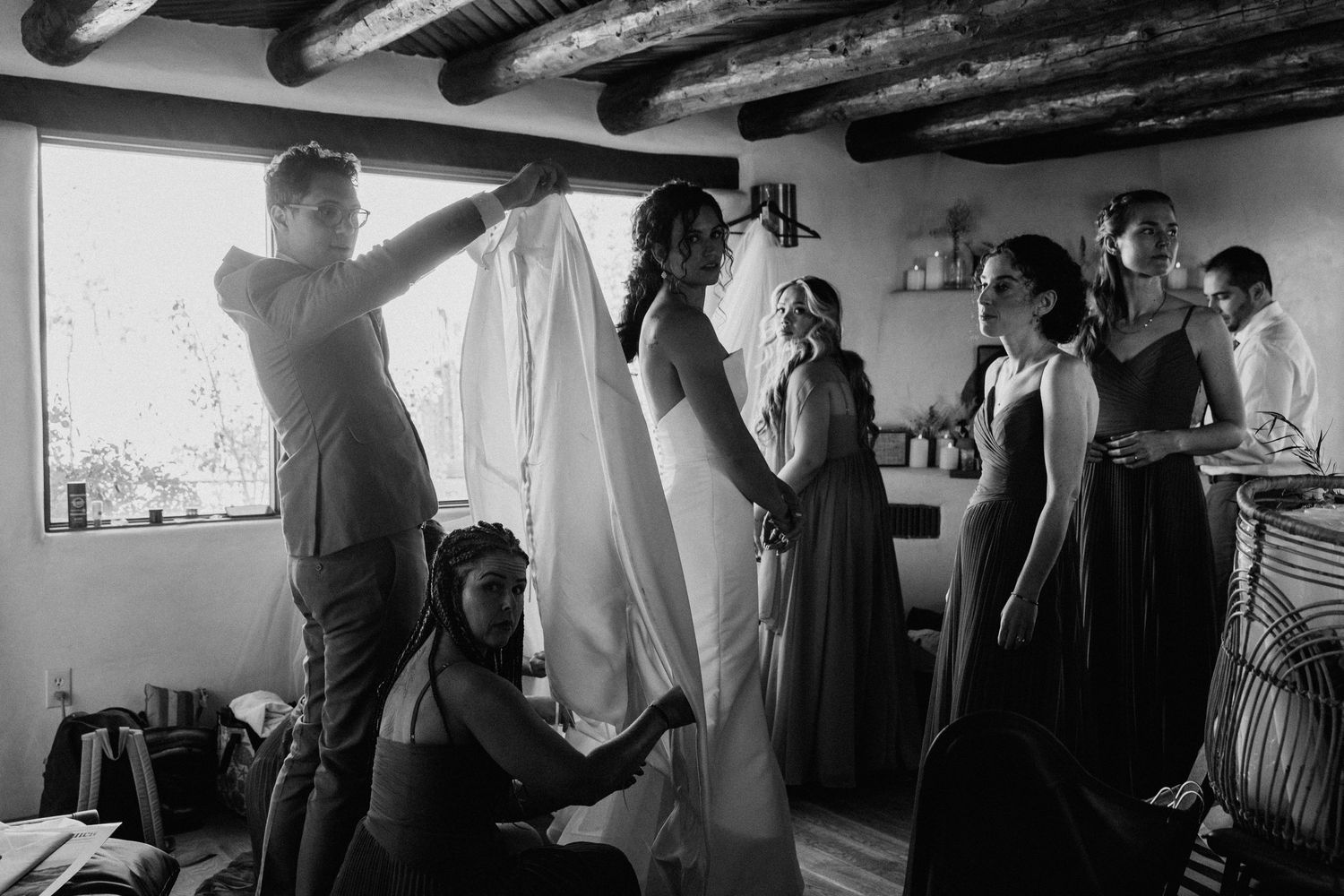 Black and white photo of wedding preparation scene with rustic wooden beams overhead.  Shot in Taos, NM by Siouxzen Kang