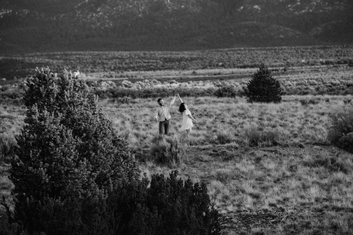 Wide landscape engagement session in Taos NM with couple in distance surrounded by vast desert terrain