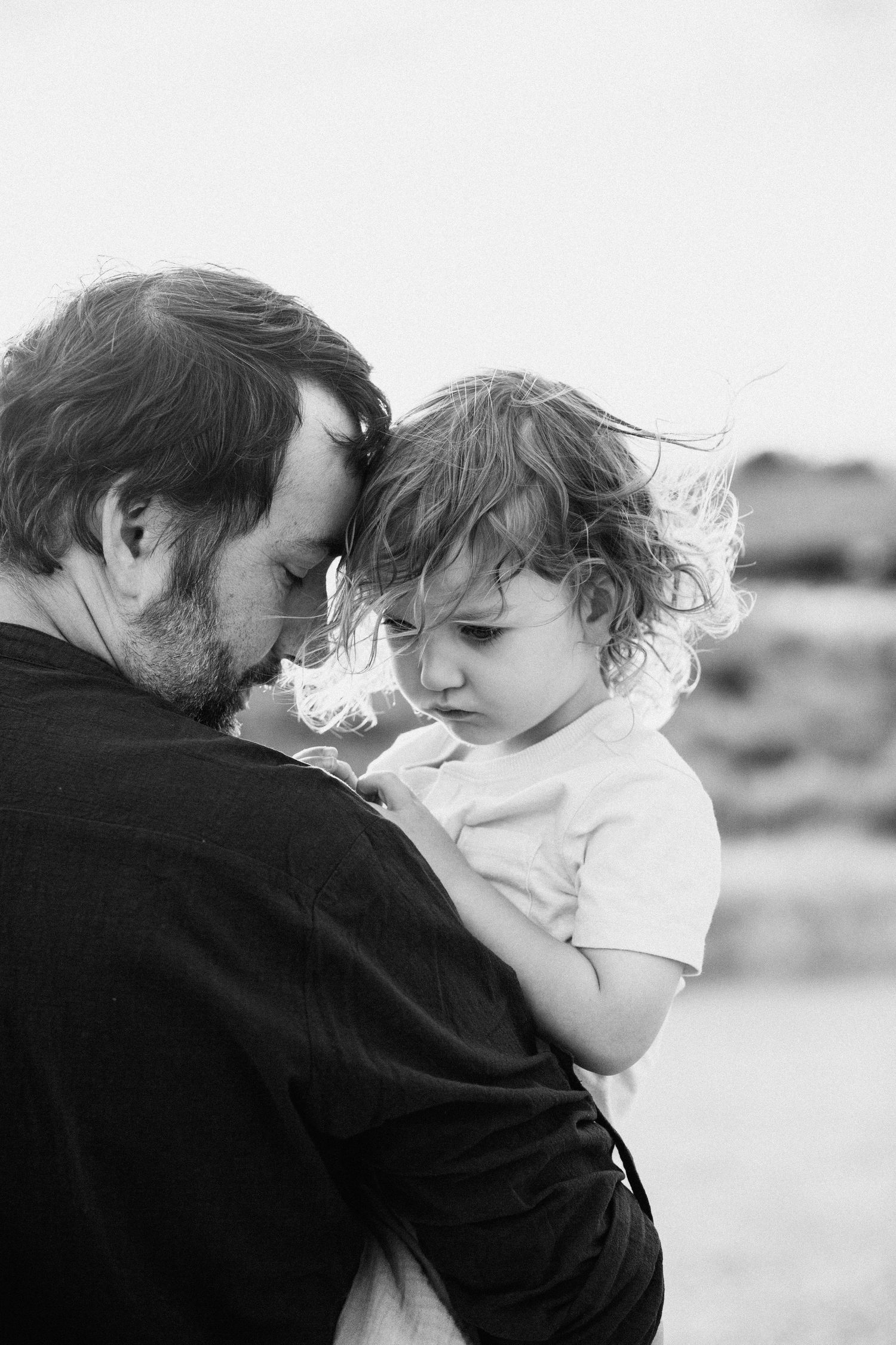 Intimate black and white portraits showing gentle embraces between two people against a minimal background.