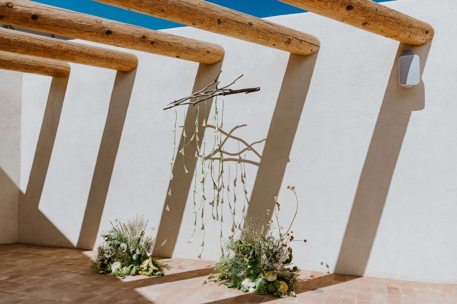 Rustic wooden beams contrast with white columns and walls in a Mediterranean-style architectural detail.