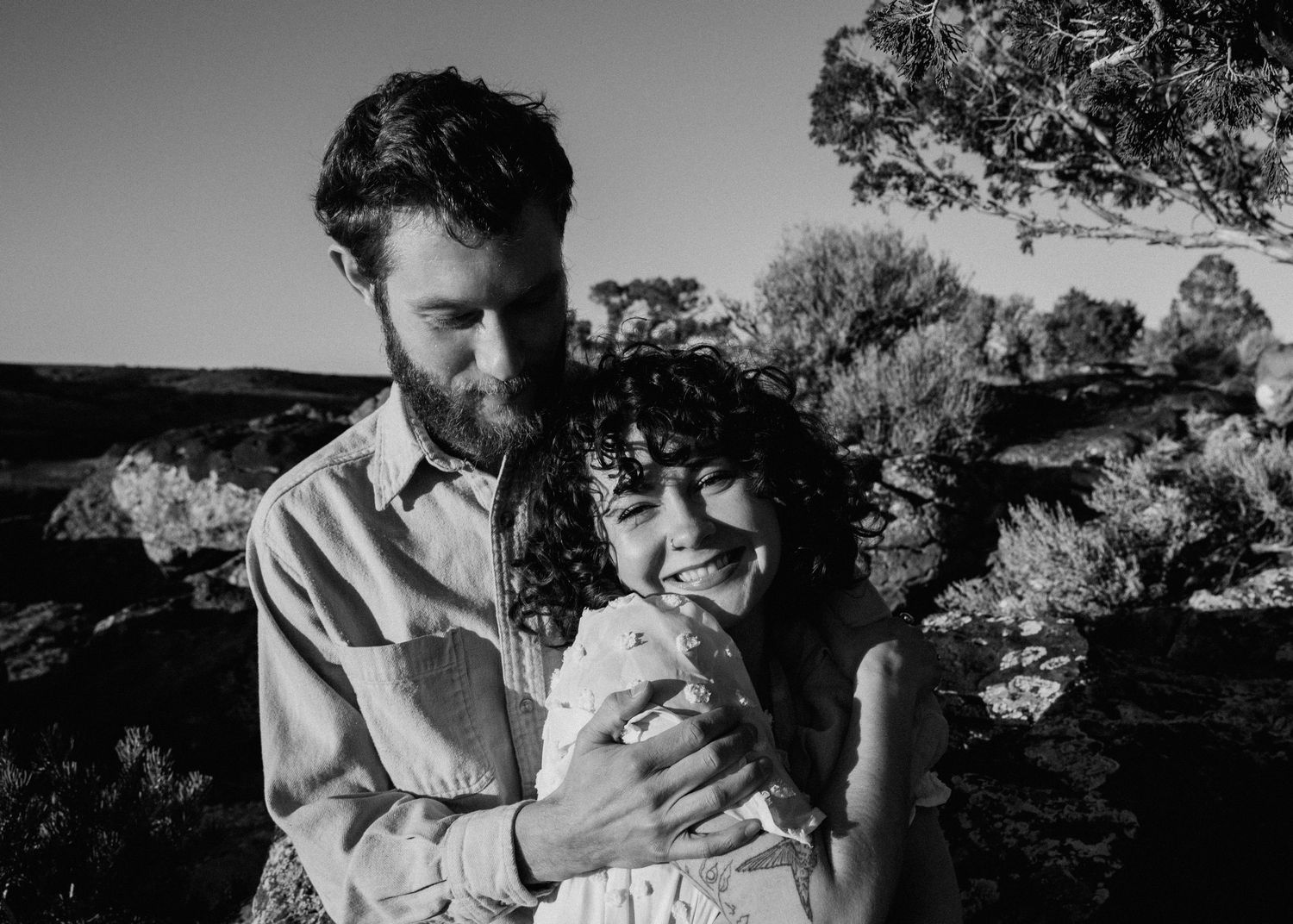 Black and white engagement session in Taos NM with couple embracing in a natural outdoor setting