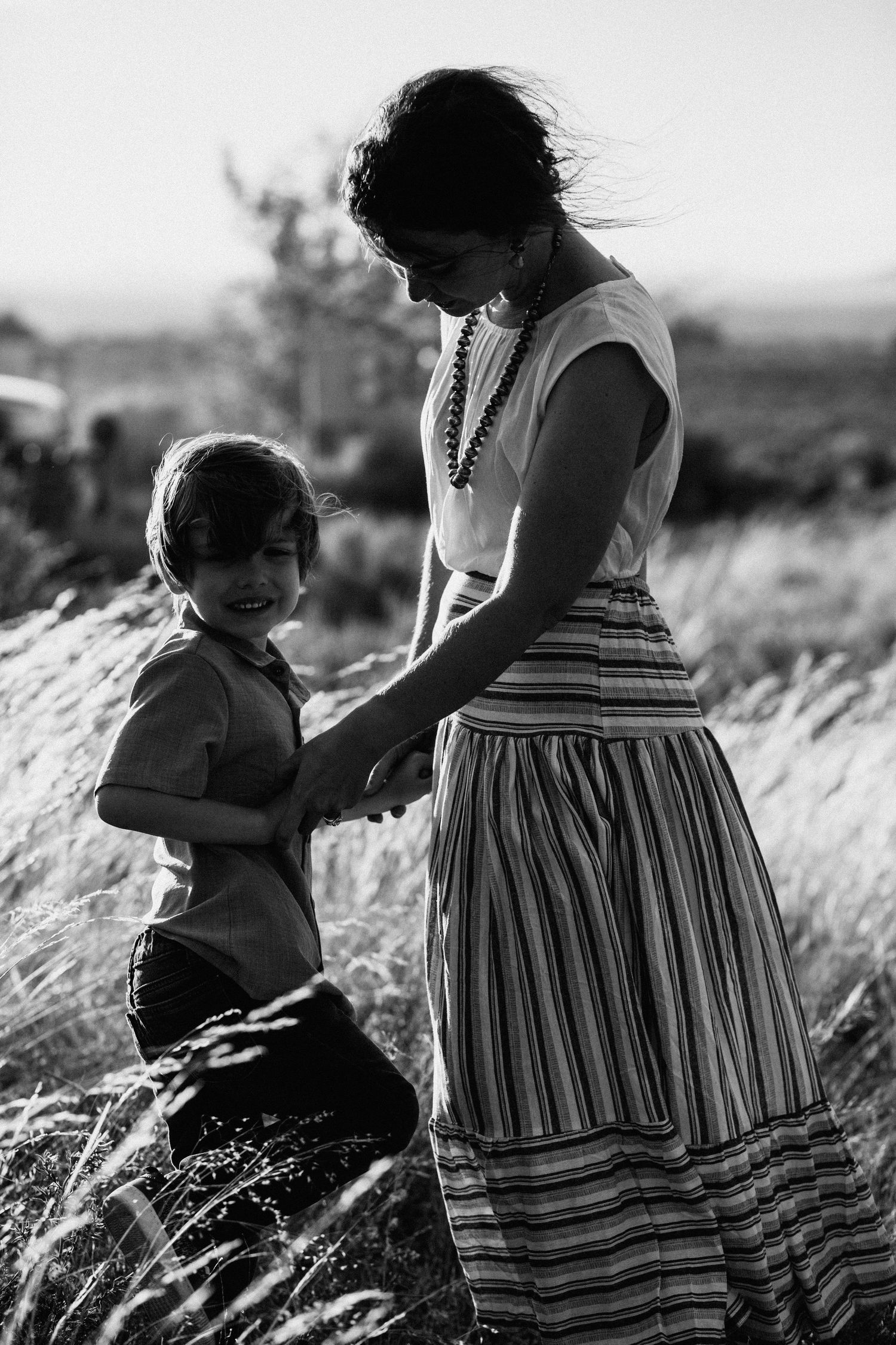 A touching black and white photo series showing tender moments between a child and adult in a field of tall grass.