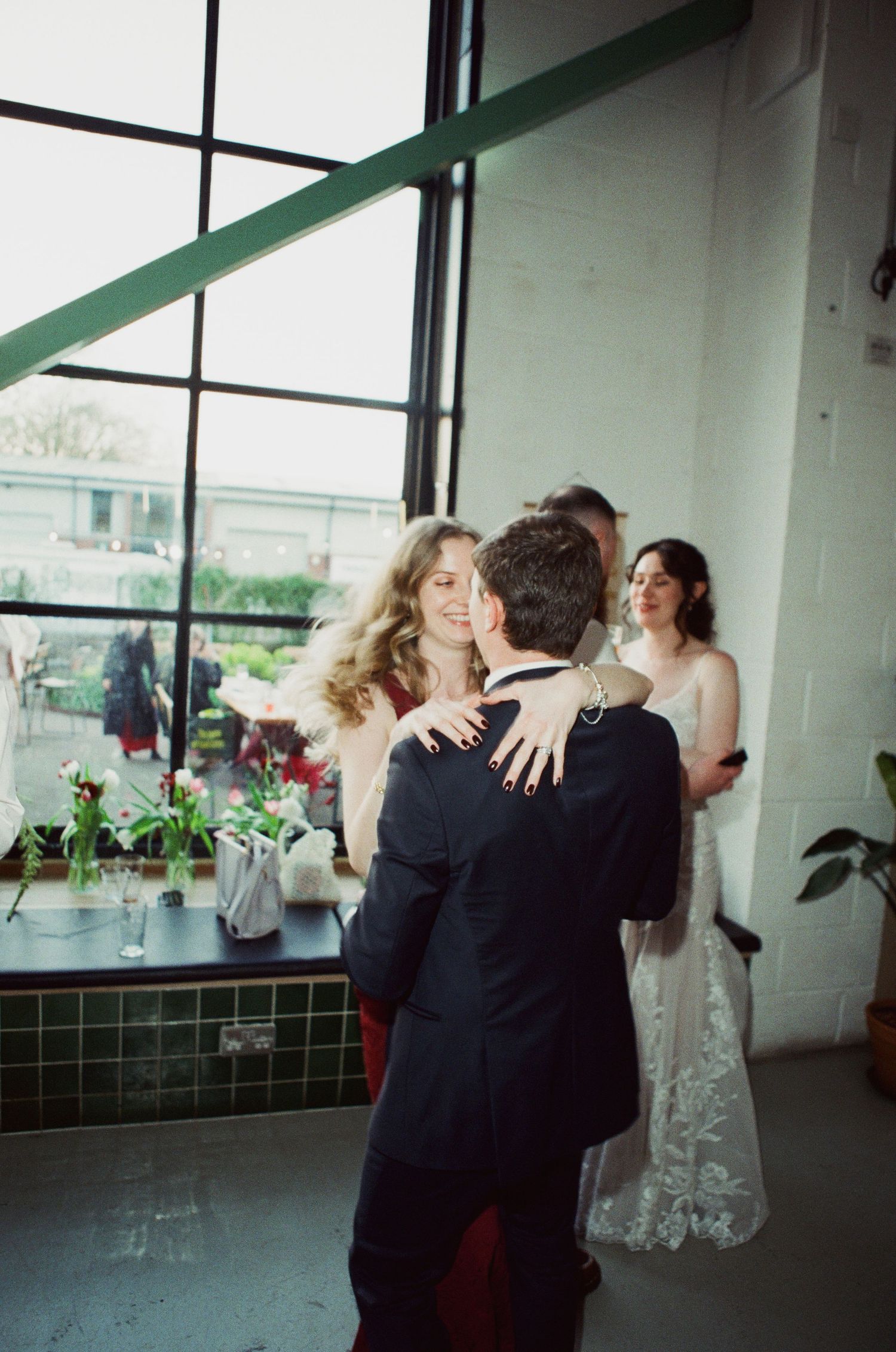 Couple sharing a tender dance near large industrial windows at a modern wedding venue reception.
