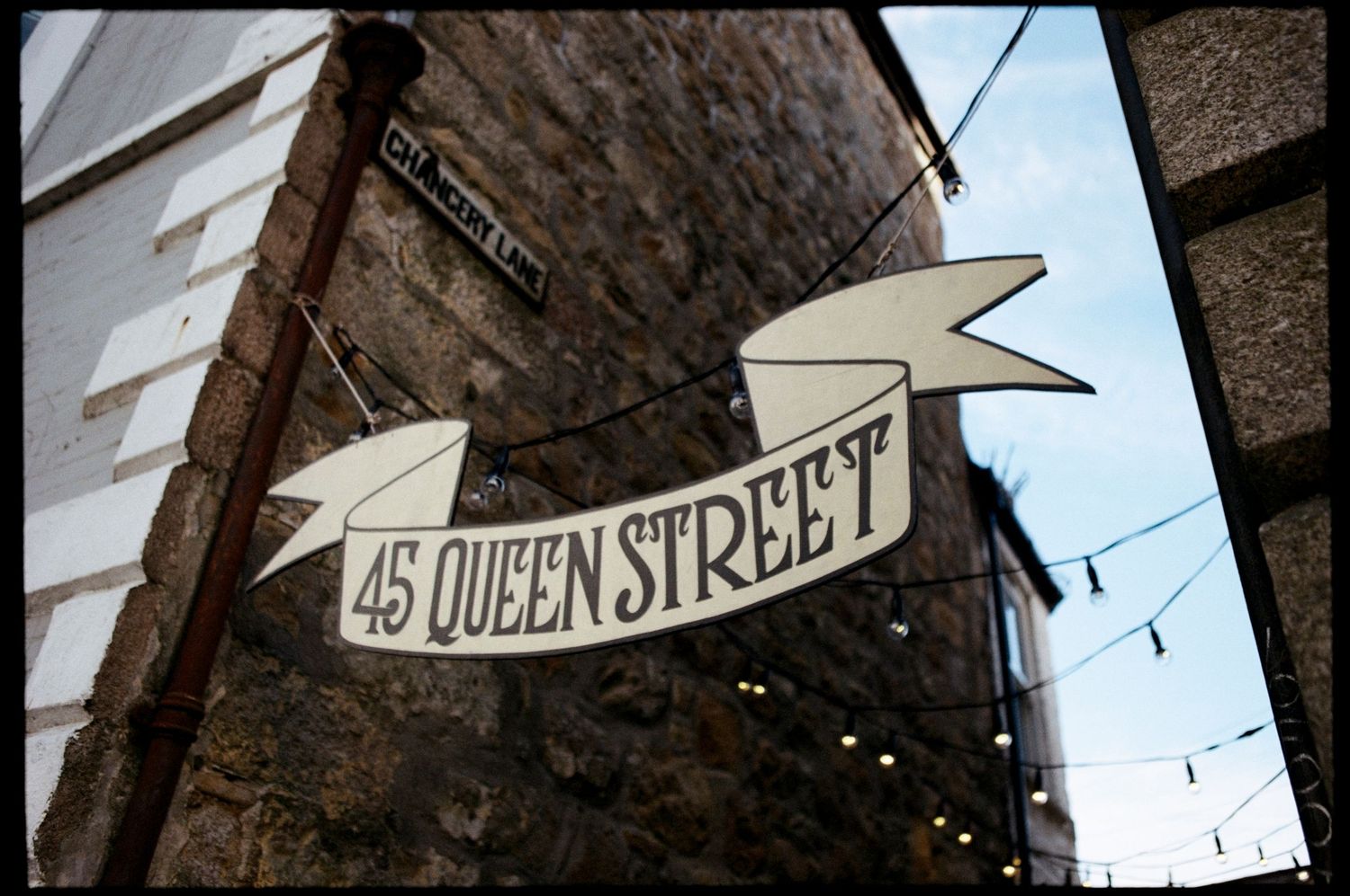 Vintage-style banner sign reading 45 Queen Street mounted on a historic stone building wall.