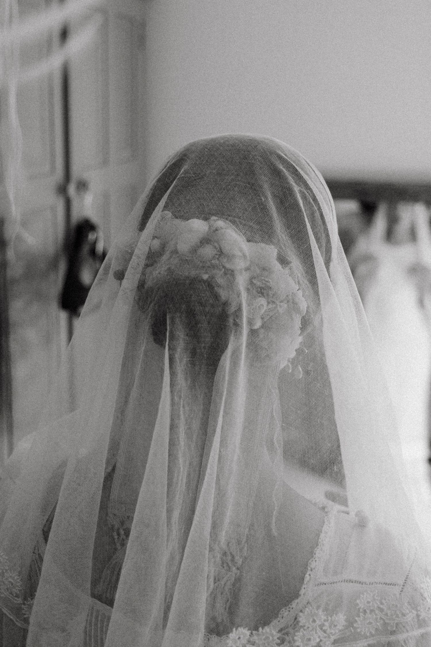 Black and white portrait of a bride wearing a delicate veil and floral hair accessories before her wedding.