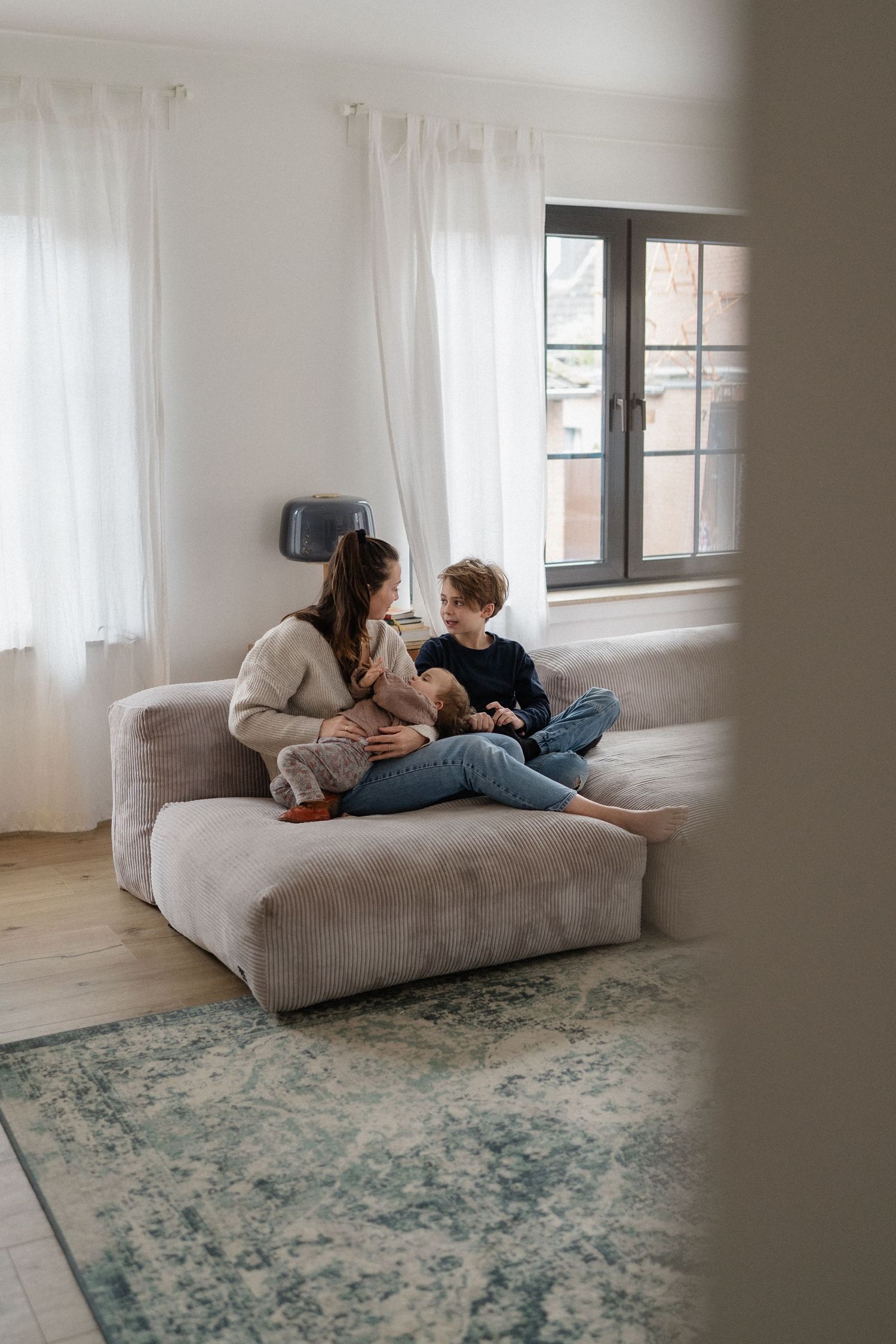 Mother and young son sitting together on a cozy sofa in a bright modern living room.