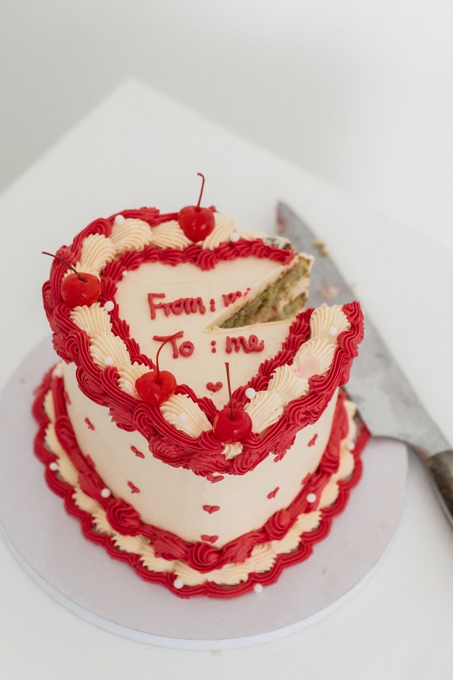Heart-shaped Valentine's cake with red frosting, cherries, and 
