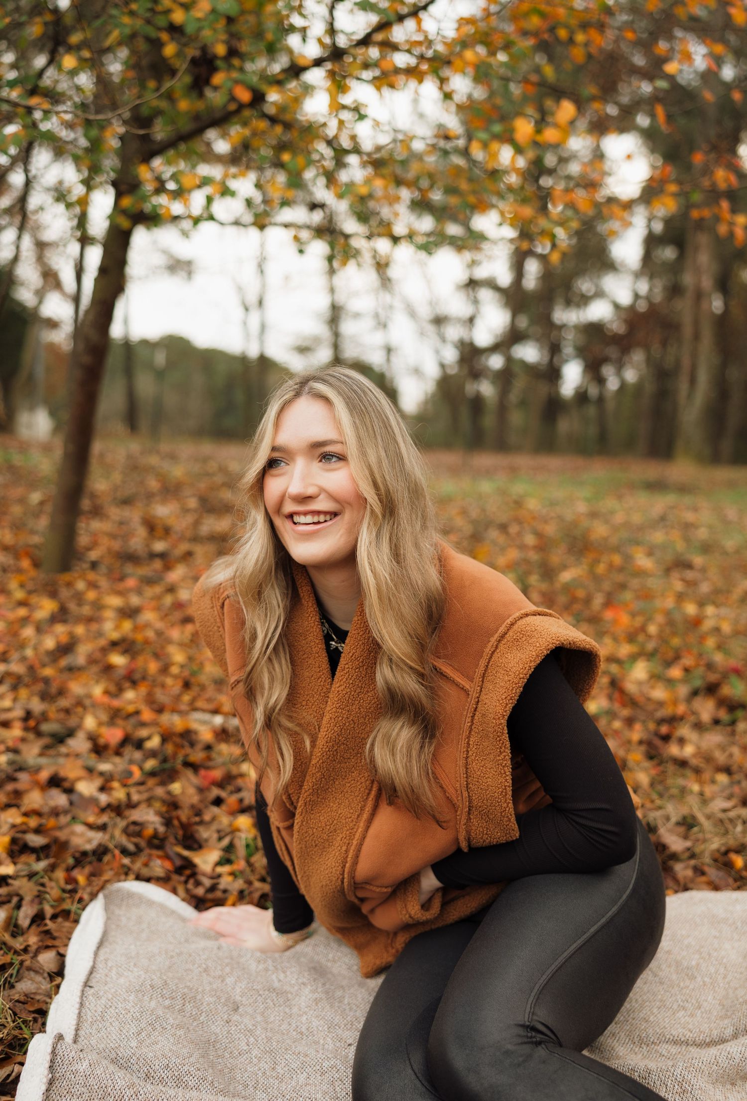 Outdoor autumn portrait with orange and brown fall foliage in background.