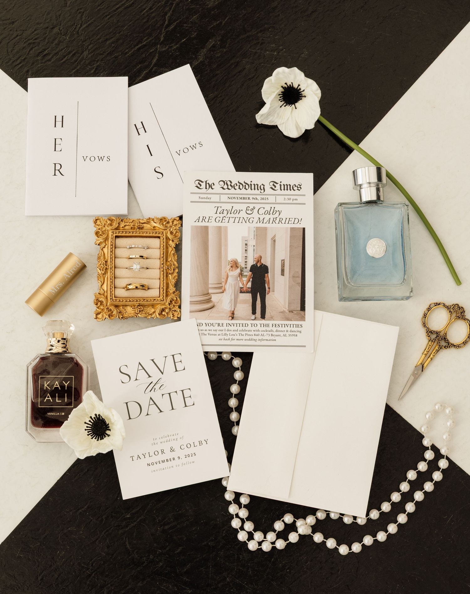 Wedding stationery flatlay with save the date cards, invitations, and pearl necklace on dark background.
