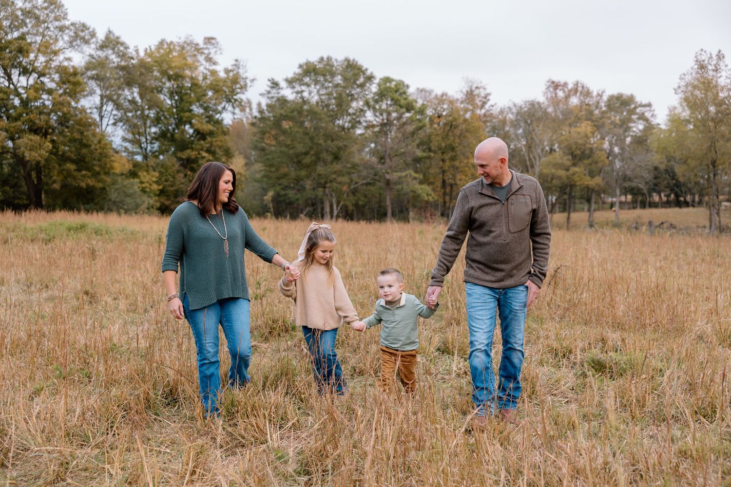 Family walking together through a golden autumn field at sunset.