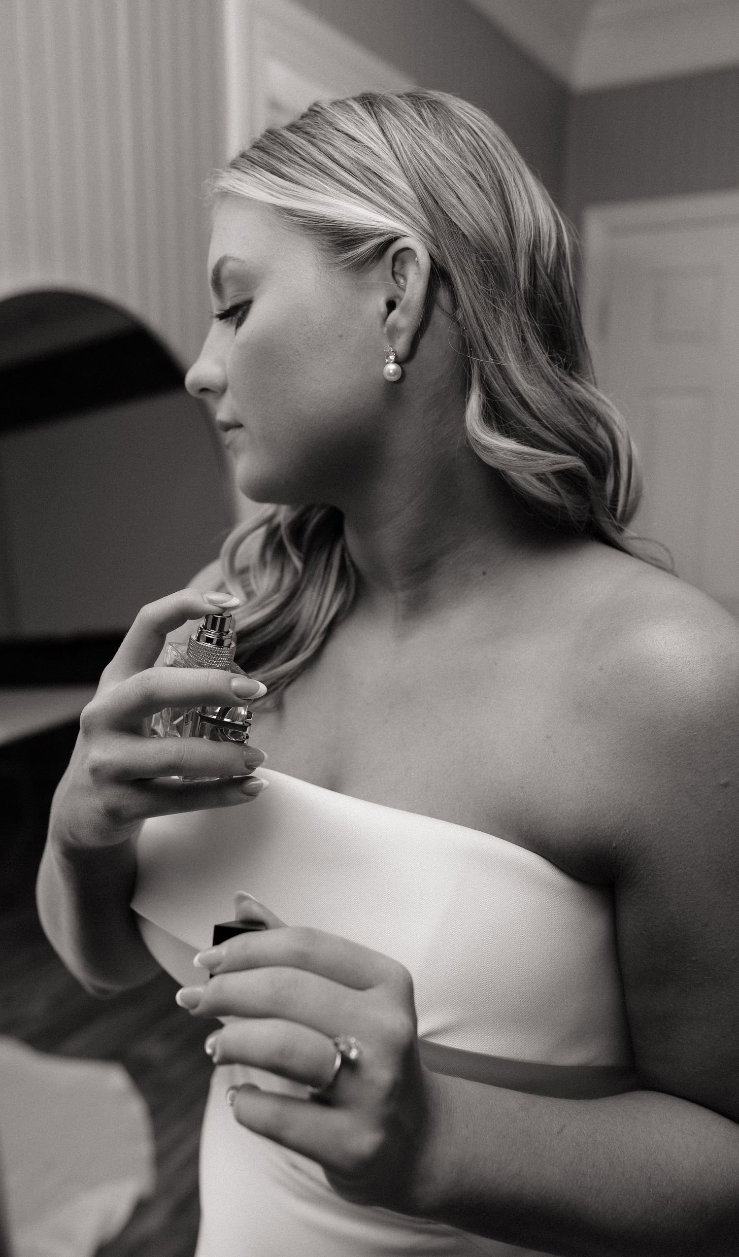 Black and white photo sequence showing someone applying perfume to their neck in an elegant strapless dress.