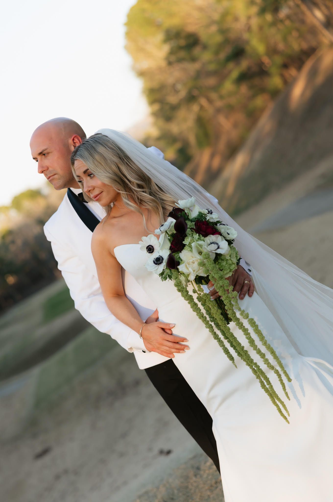 Sunset wedding portraits with dramatic lighting and cascading bouquet details.