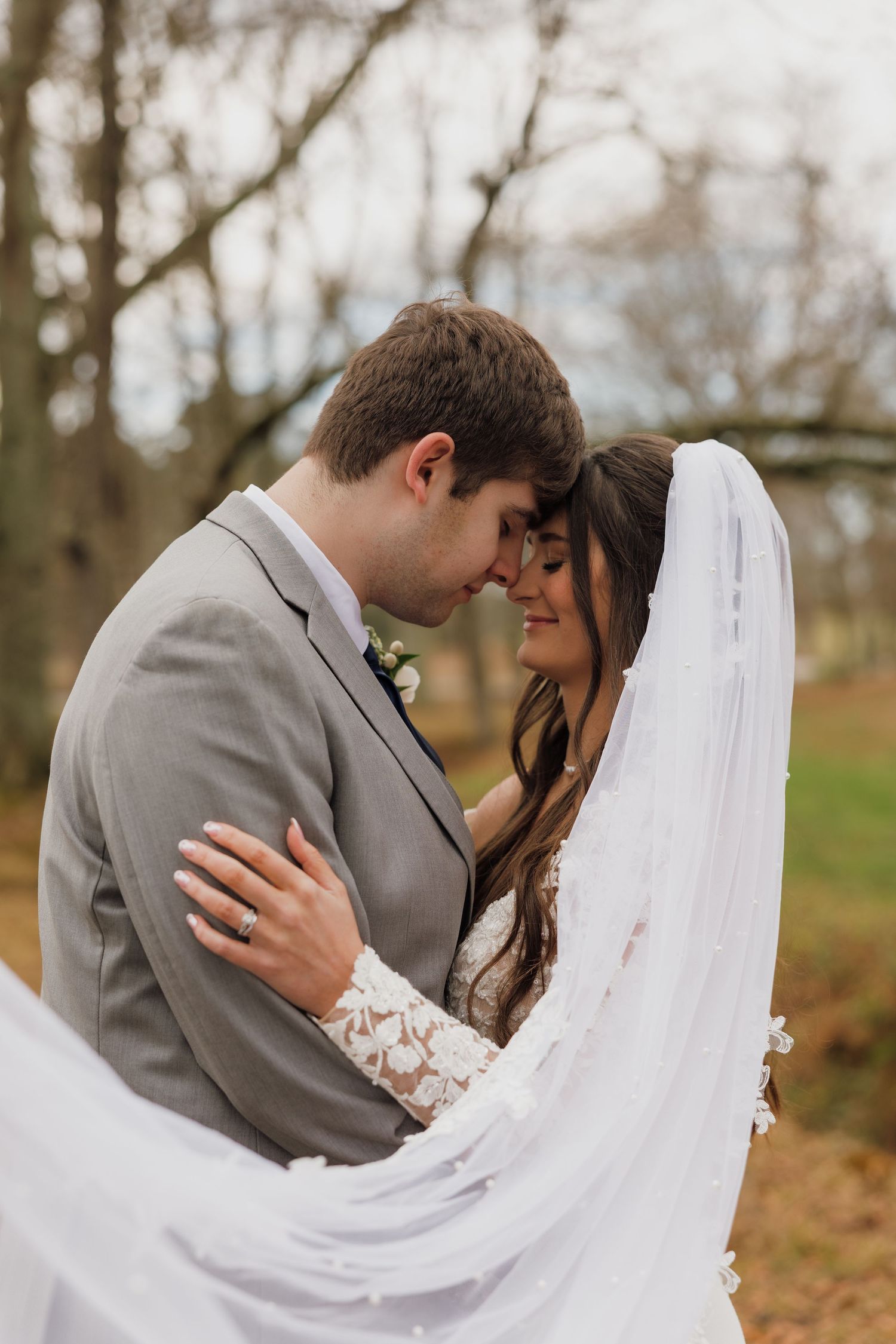 Romantic wedding portrait captured in soft natural light with flowing veil movement.